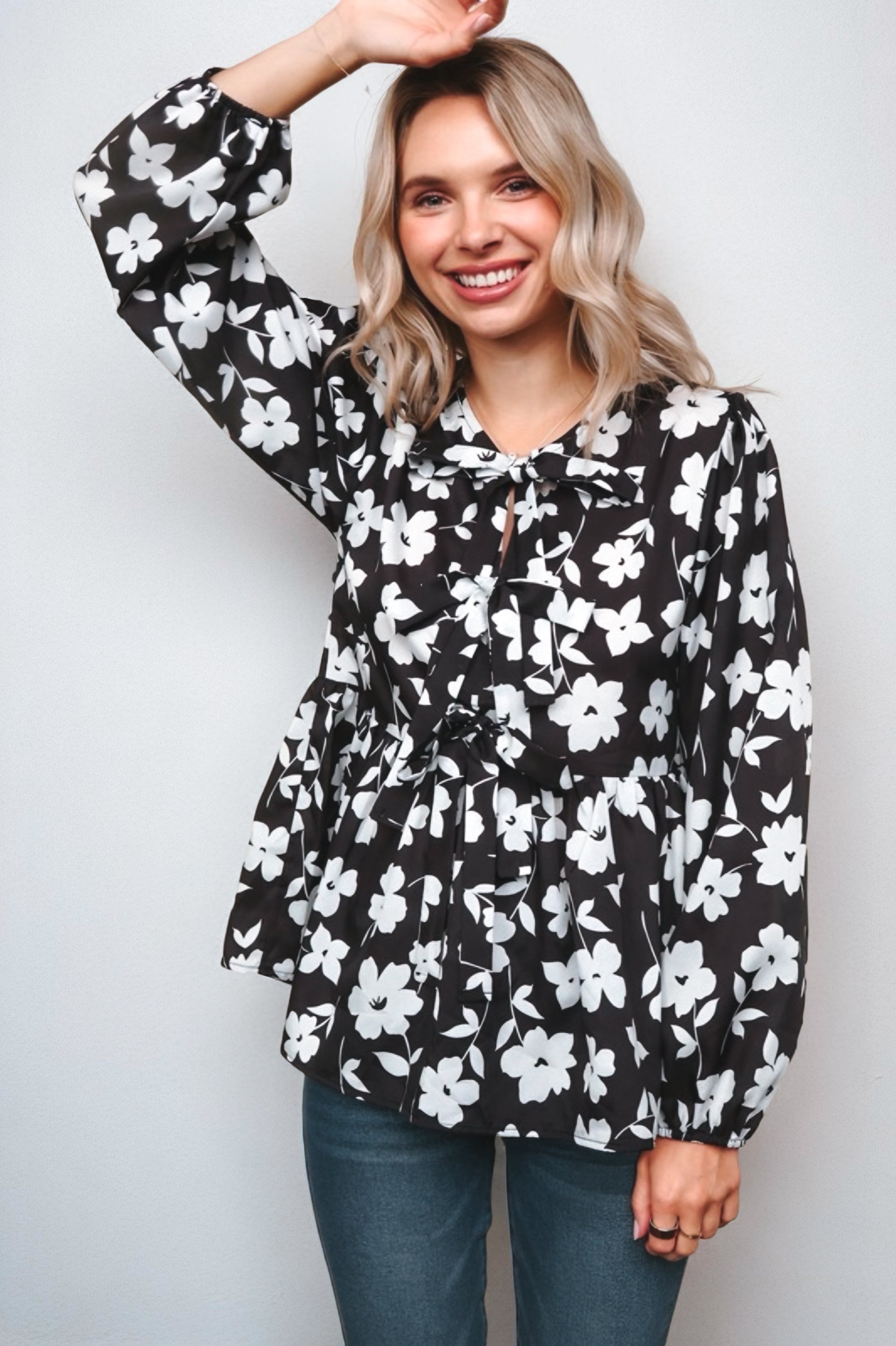 Fleur with Flair Double Bow Babydoll Top in black and white floral design with long sleeves, bow accents, and a relaxed fit worn by smiling woman in casual jeans.