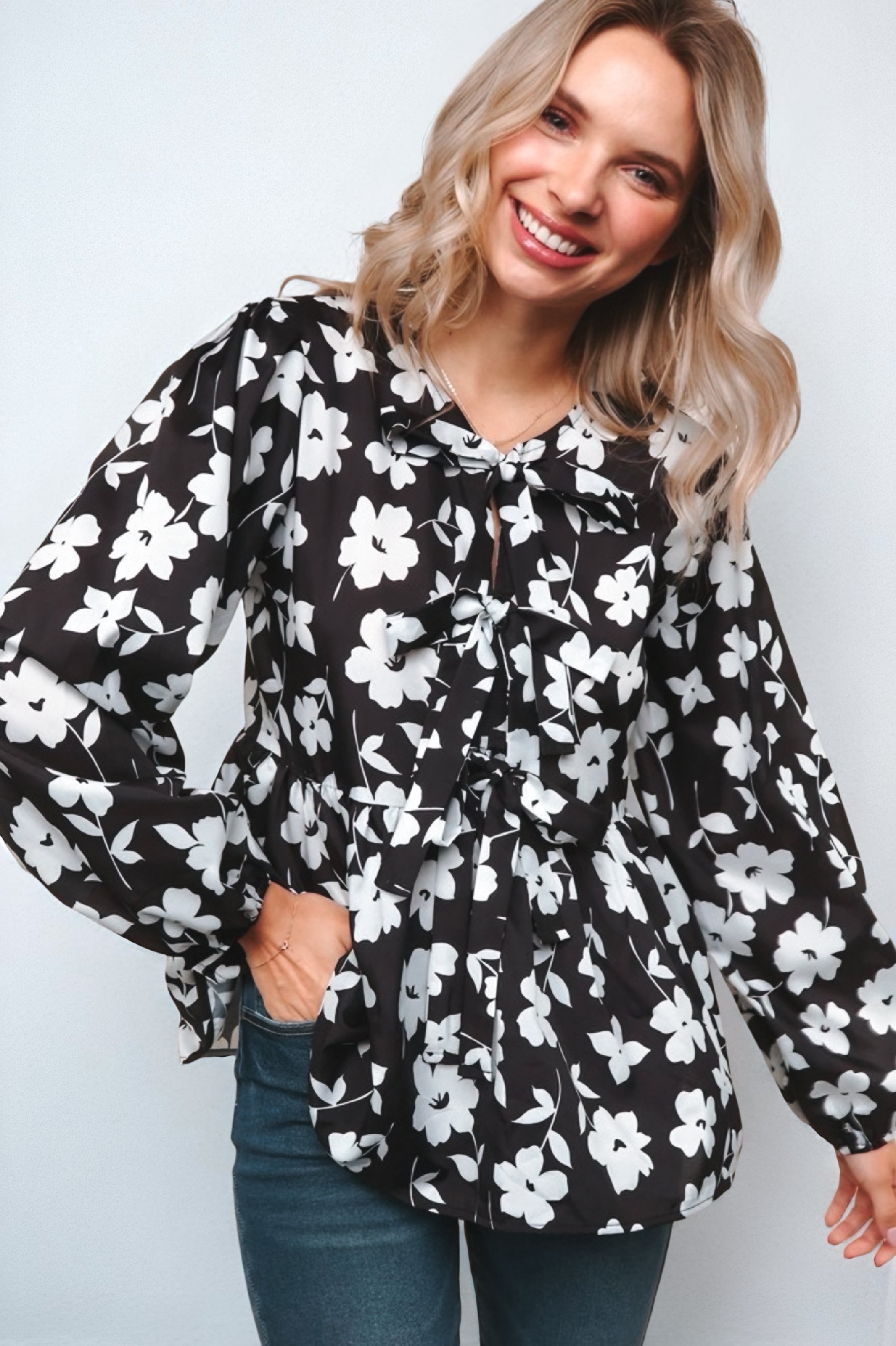 Fleur with Flair Double Bow Babydoll Top in black and white floral pattern with puffed long sleeves and playful bow ties worn by smiling blonde woman in casual jeans.