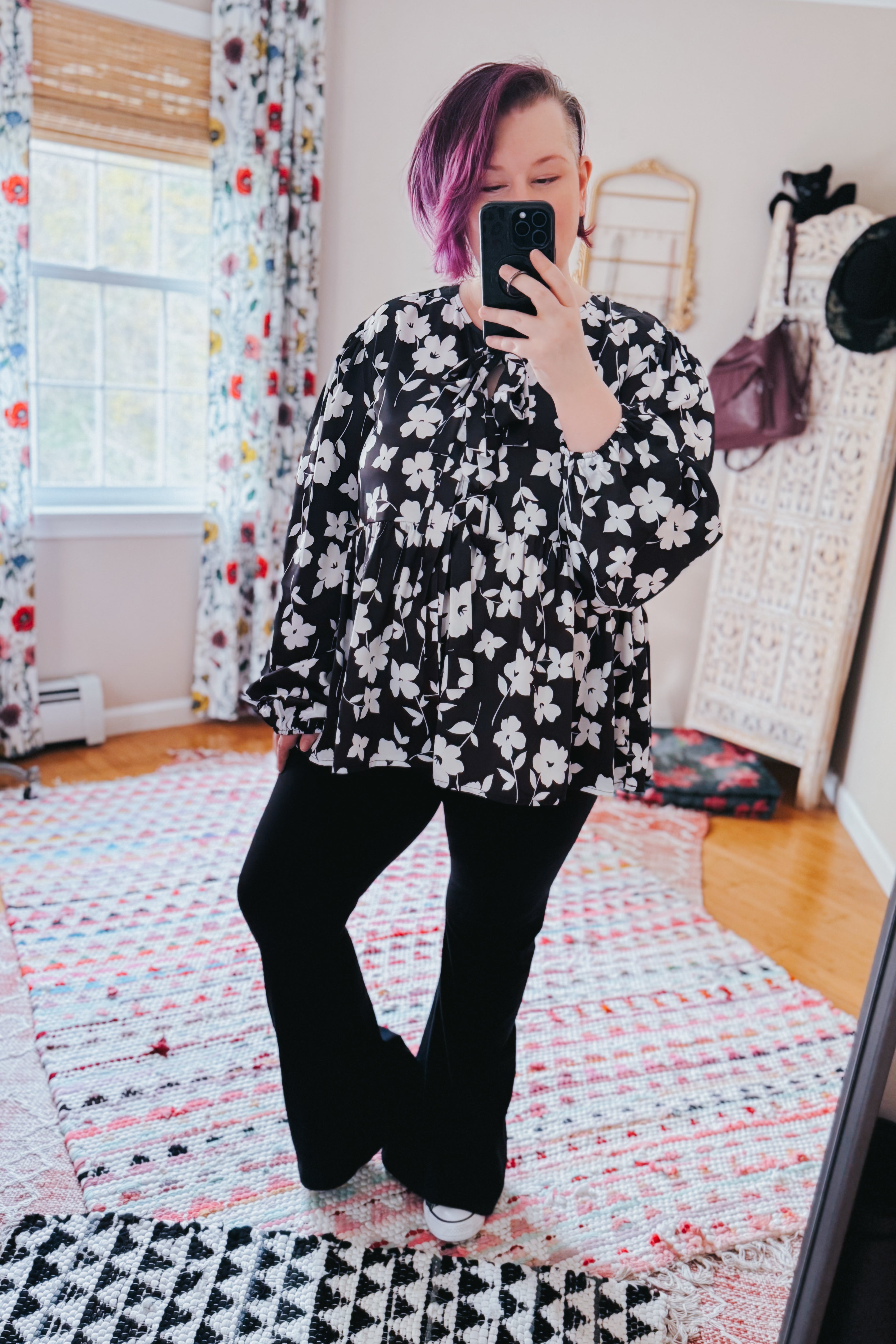 Fleur with Flair Double Bow Babydoll Top in black and white floral print, worn with black pants in a bright room with patterned curtains and cozy decor.