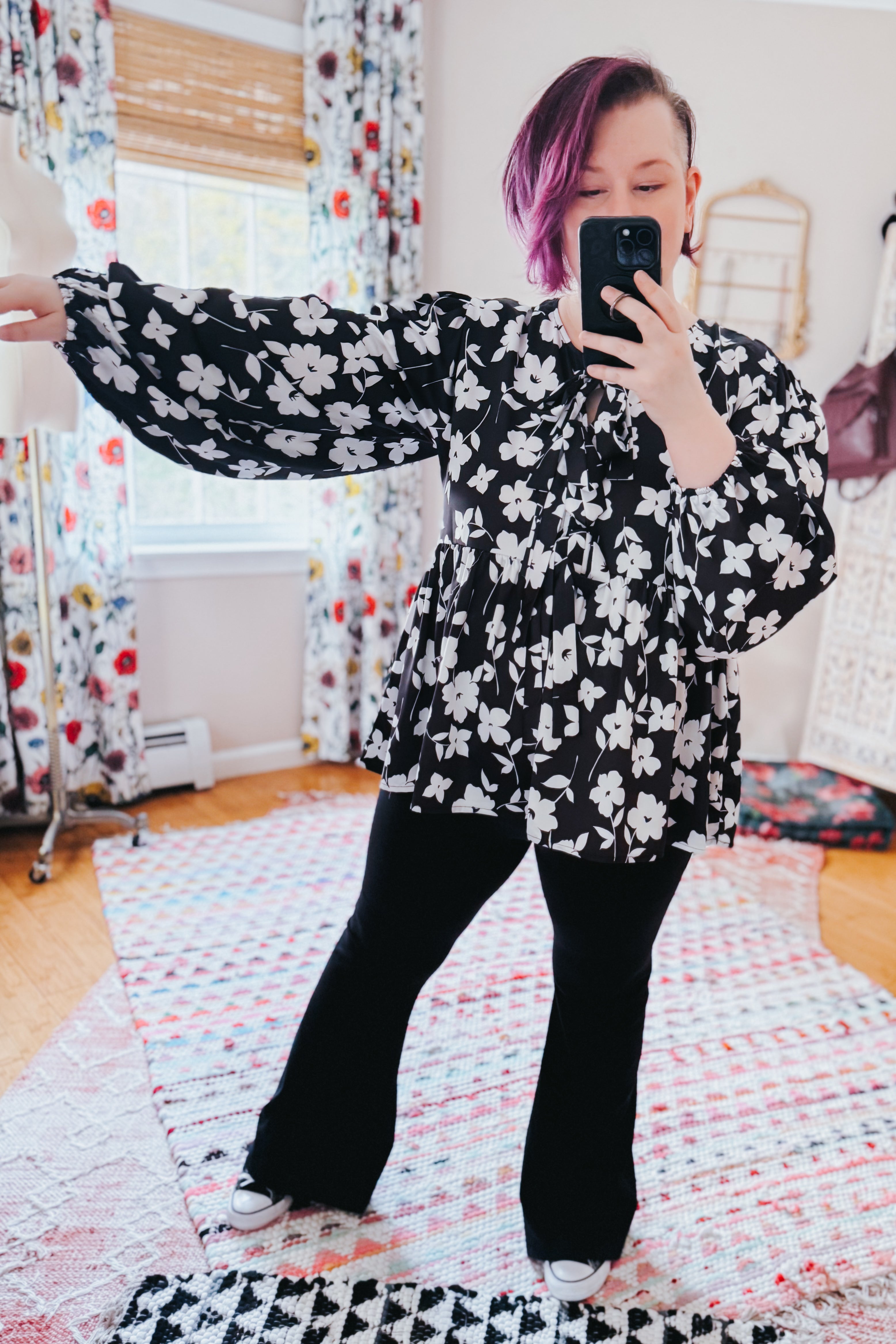 Fleur with Flair Double Bow Babydoll Top in black and white floral pattern with billowy sleeves, styled with black pants and casual shoes in a bright, cozy room.