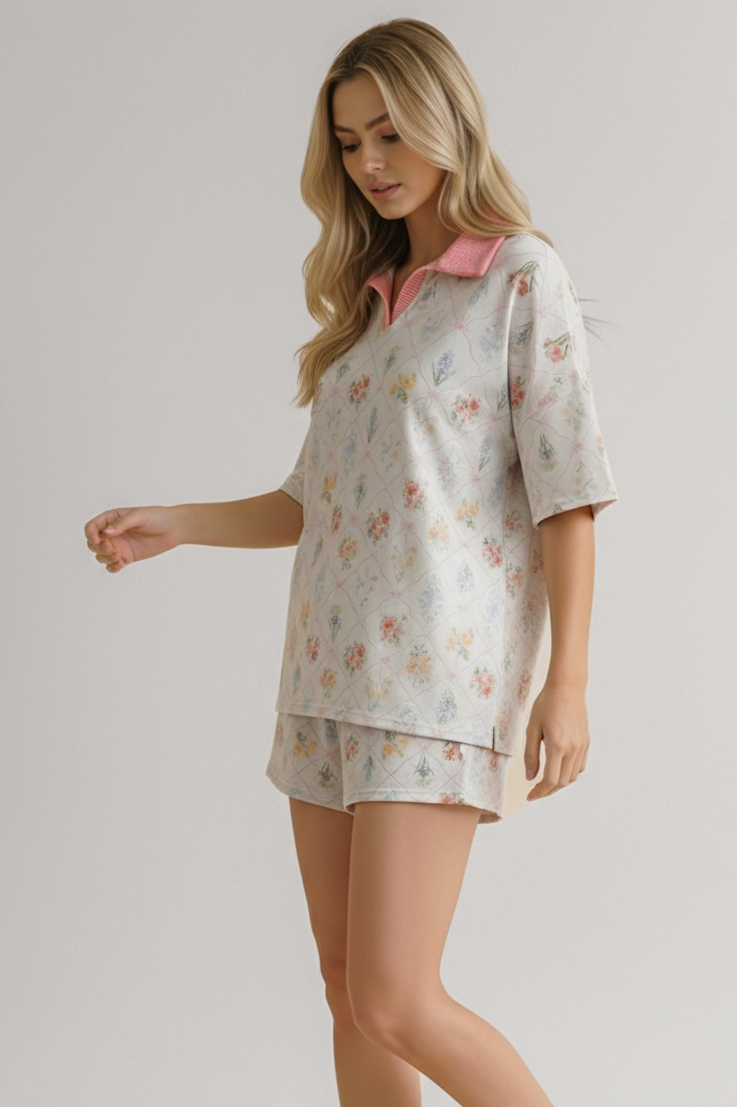 Woman wearing ivory floral garden matching short set with pink collar, posing relaxed against neutral background
