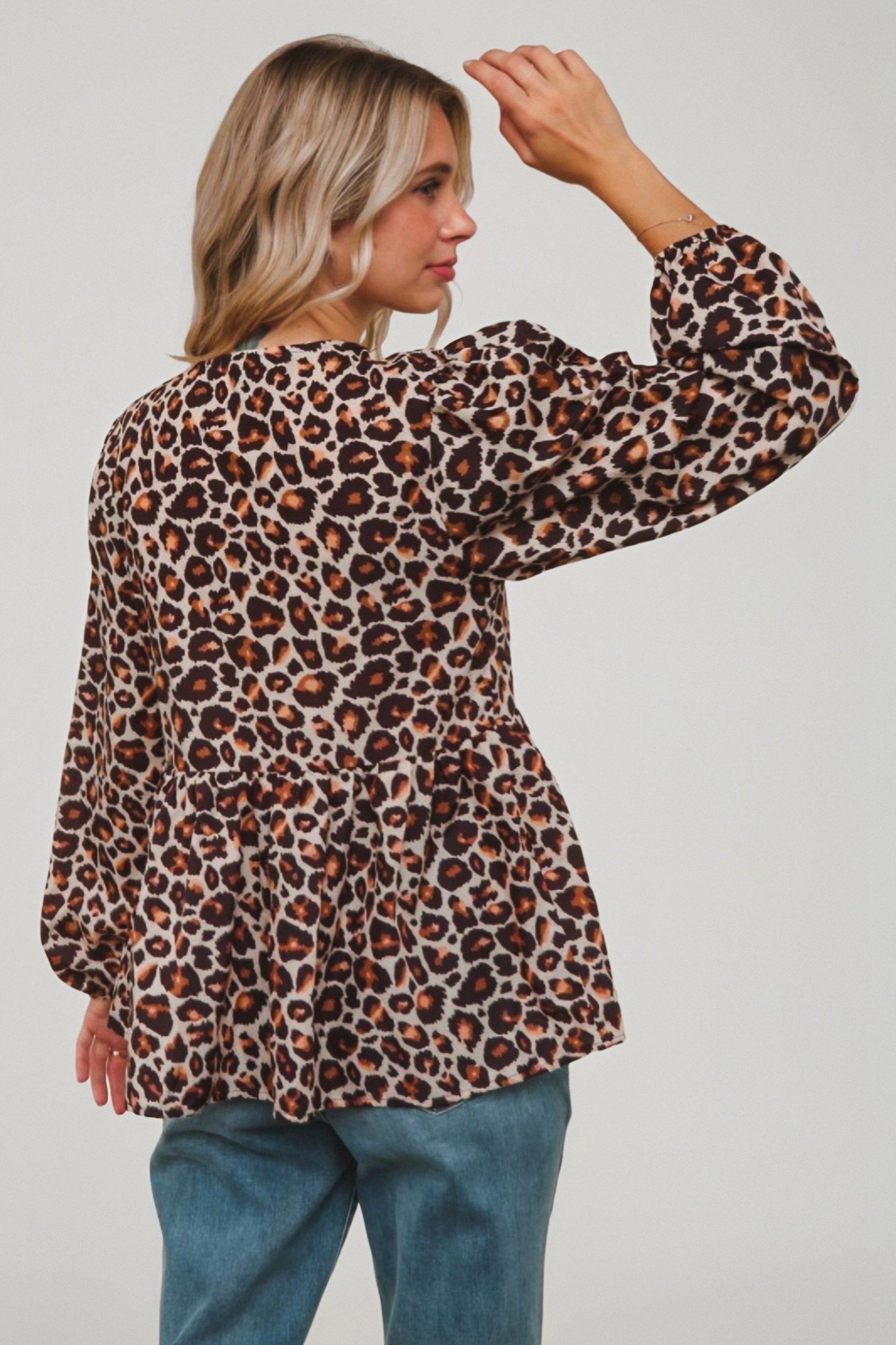 Woman wearing brown animal print babydoll blouse with gathered waist and long puff sleeves viewed from behind