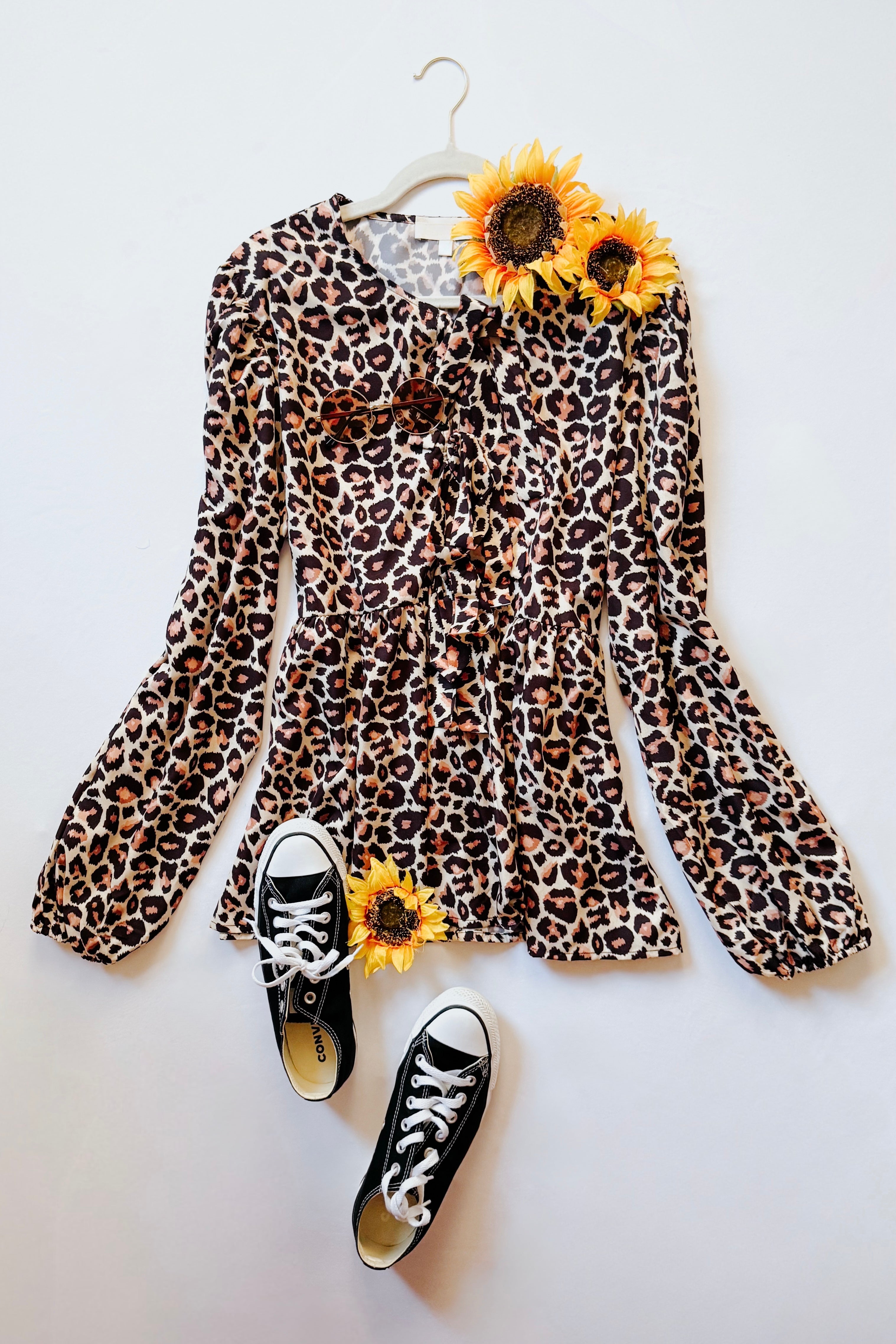 Brown leopard print babydoll blouse with long puff sleeves styled with black sneakers and sunflowers on white background