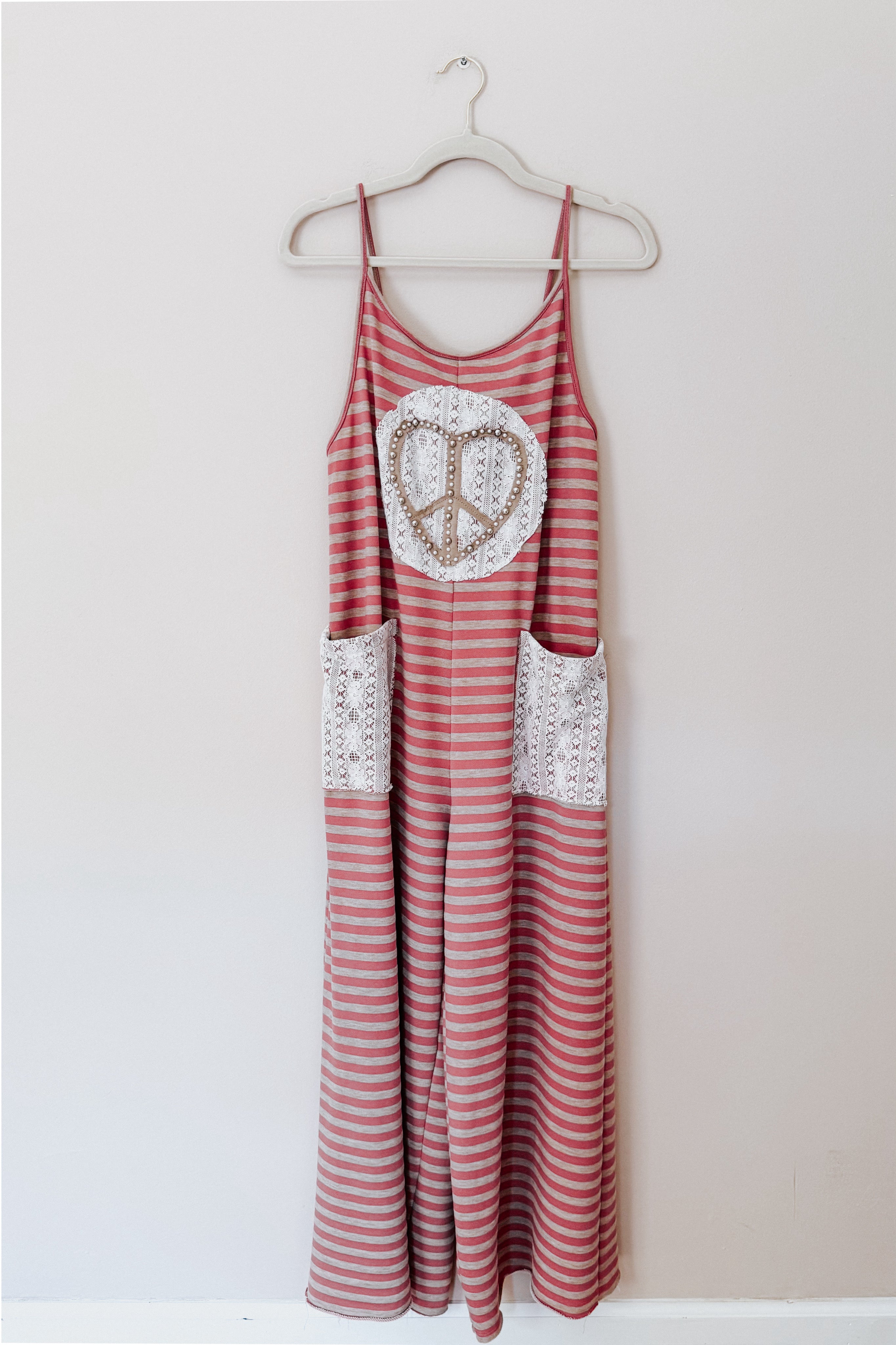 Red striped sleeveless jumpsuit with wide legs featuring lace patch pockets and large lace peace sign applique on front
