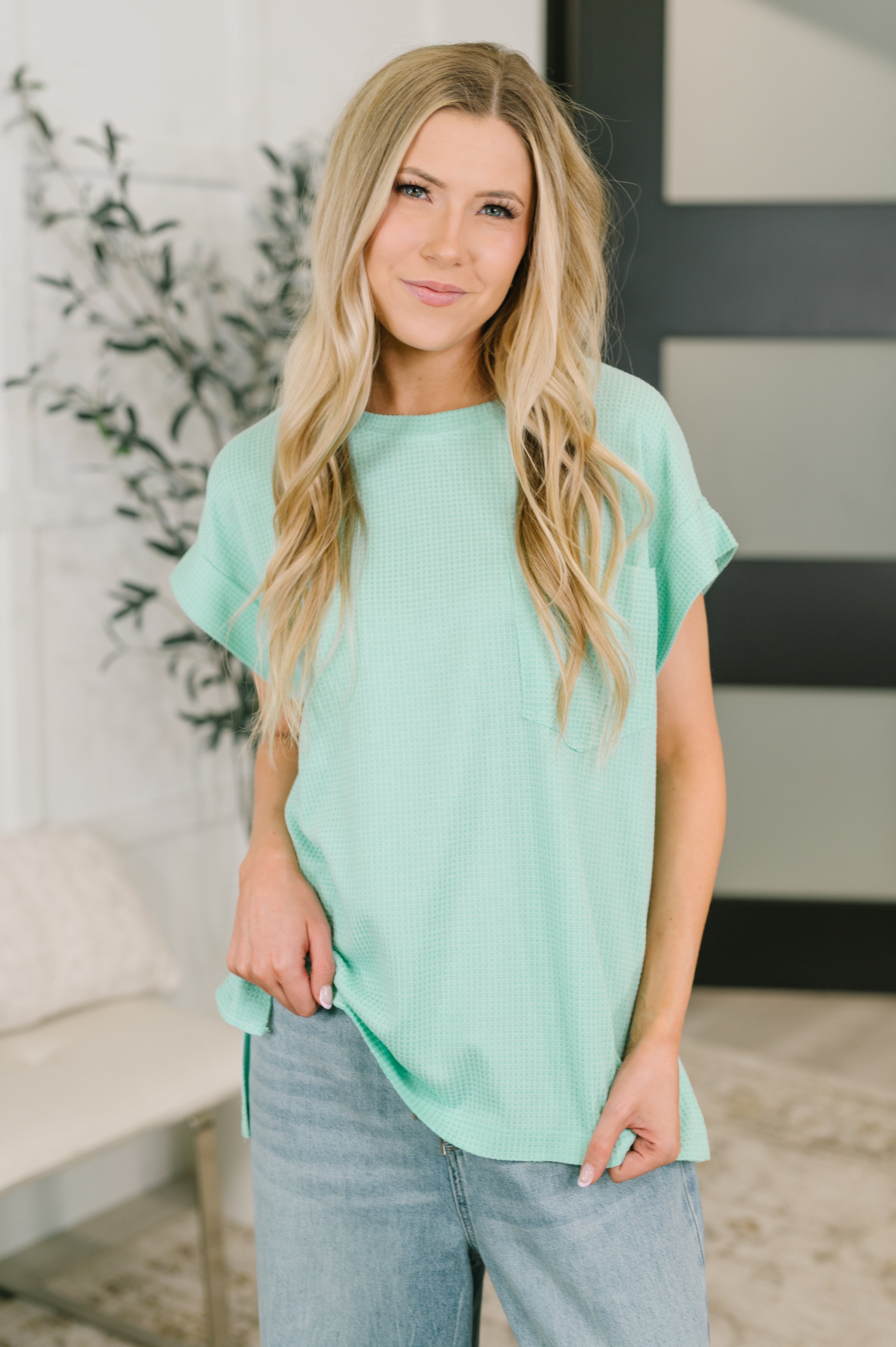 Woman wearing a mint waffle knit relaxed tee paired with light denim, styled in a free-spirited eclectic setting