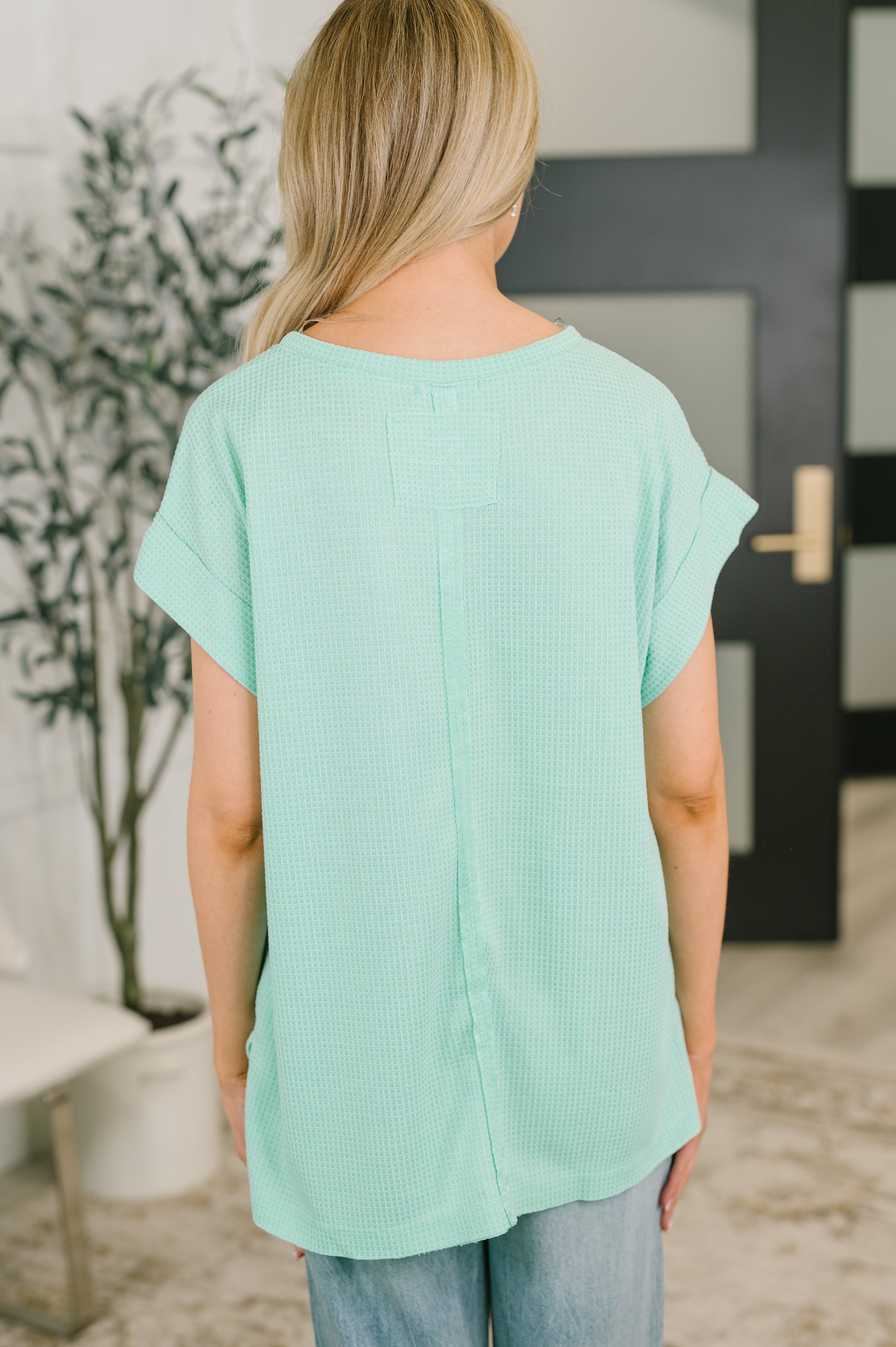 Back view of mint waffle knit relaxed tee with rolled sleeves styled in an eclectic, size-inclusive setting