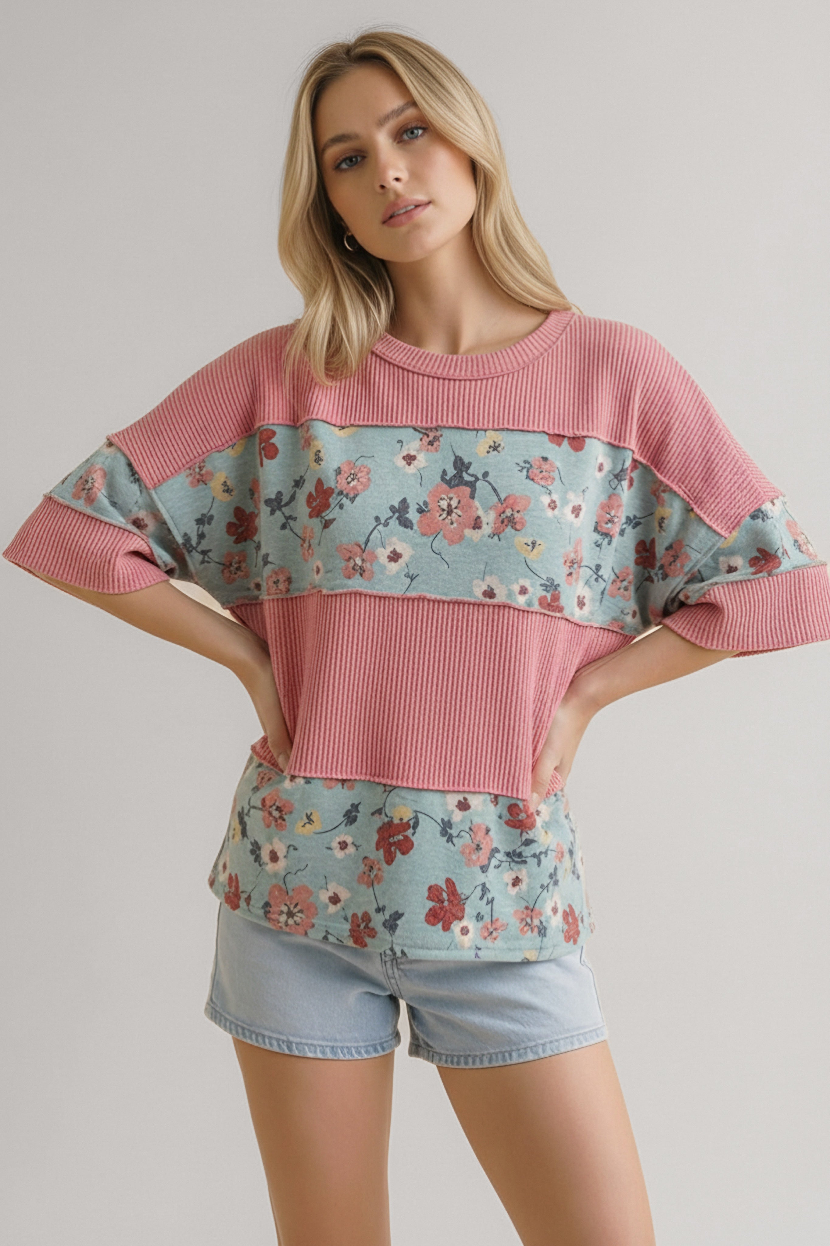 Woman wearing pink ribbed top with floral colorblock details paired with light denim shorts in casual pose