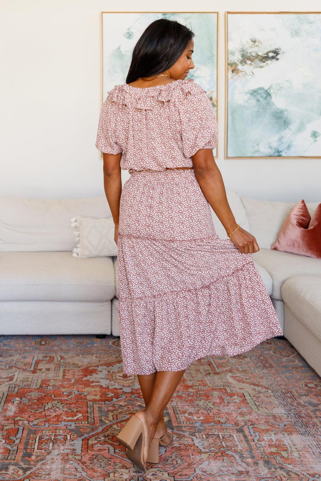 Woman showing back of rose floral dress with ruffled collar and puff sleeves standing indoors in living room
