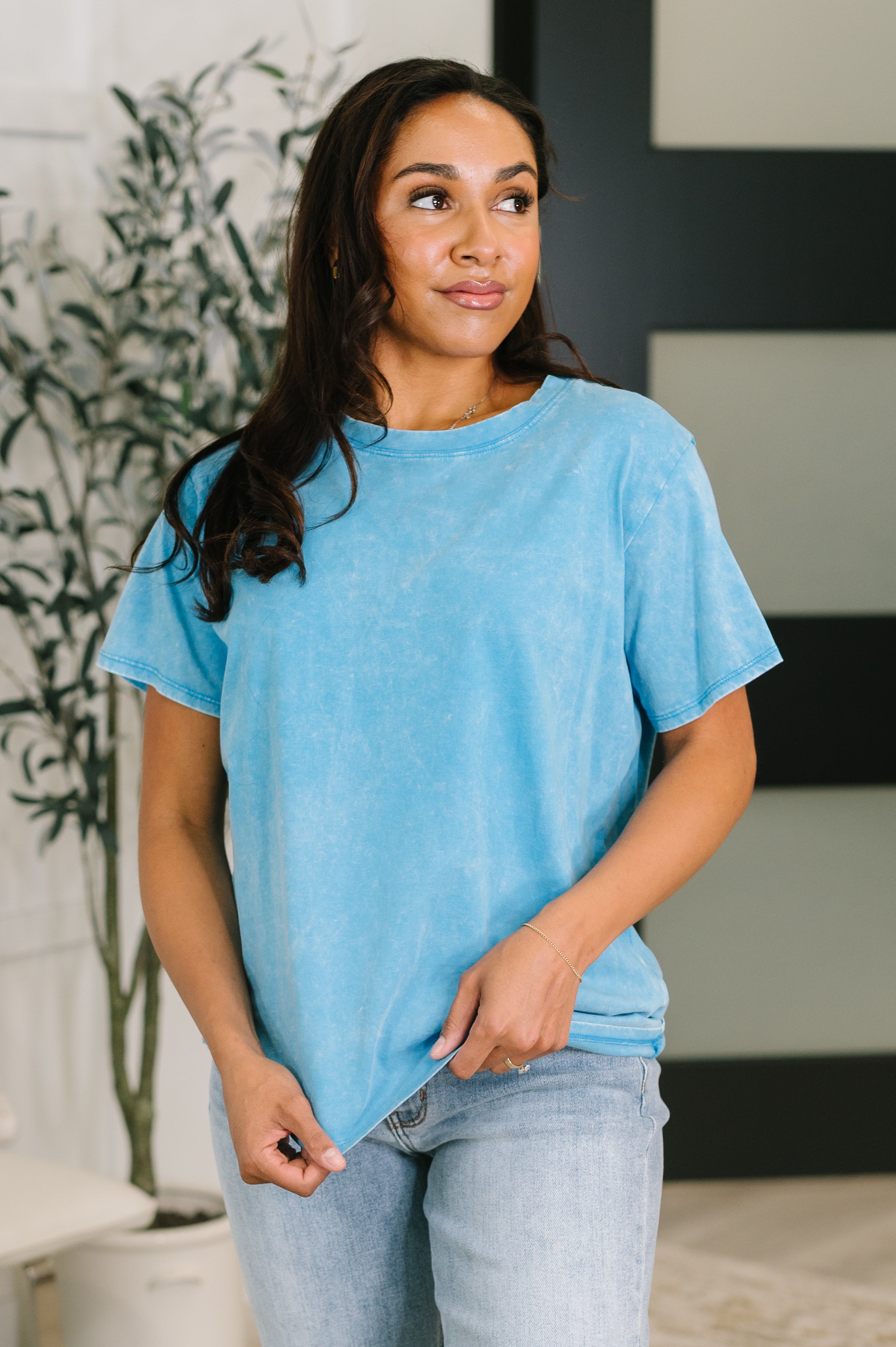 Woman wearing soft deep sky blue mineral wash tee with relaxed fit paired with light wash jeans indoors