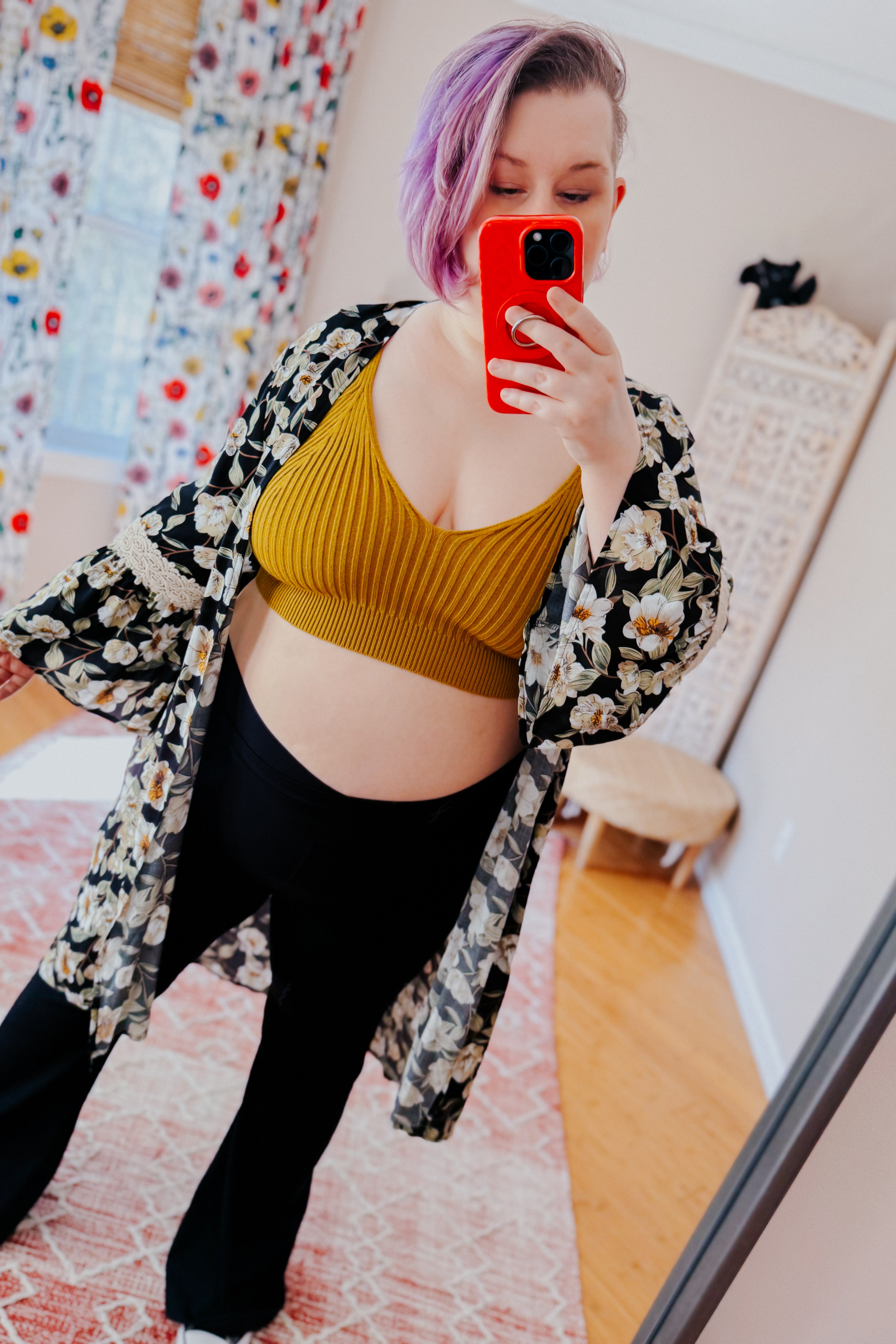 Woman with short purple hair taking mirror selfie wearing mustard rib knit brami bralette with black floral kimono and black pants indoors
