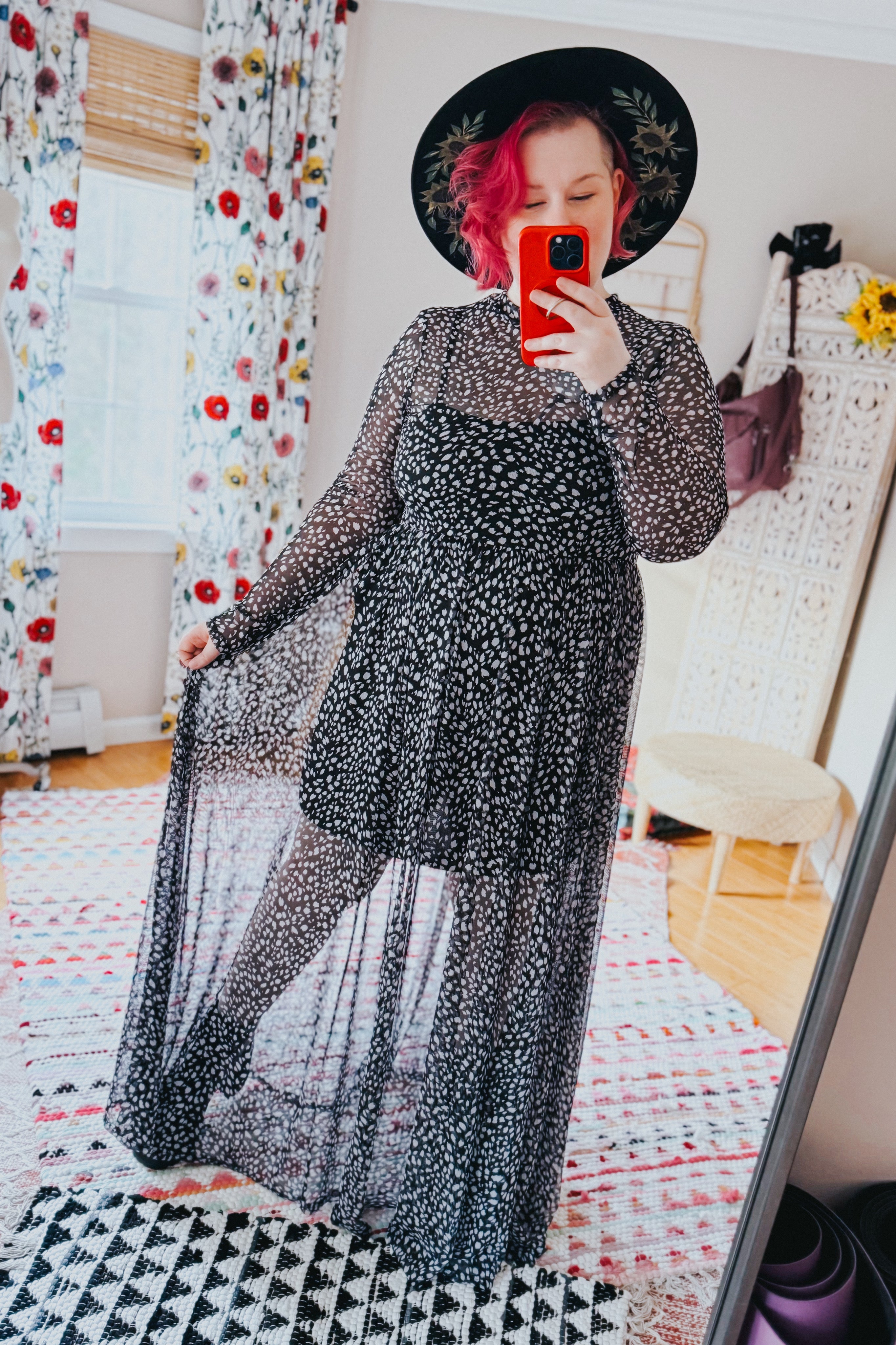 Woman taking mirror selfie wearing black Hendrix long sleeve animal print mesh maxi dress and black wide-brim hat indoors
