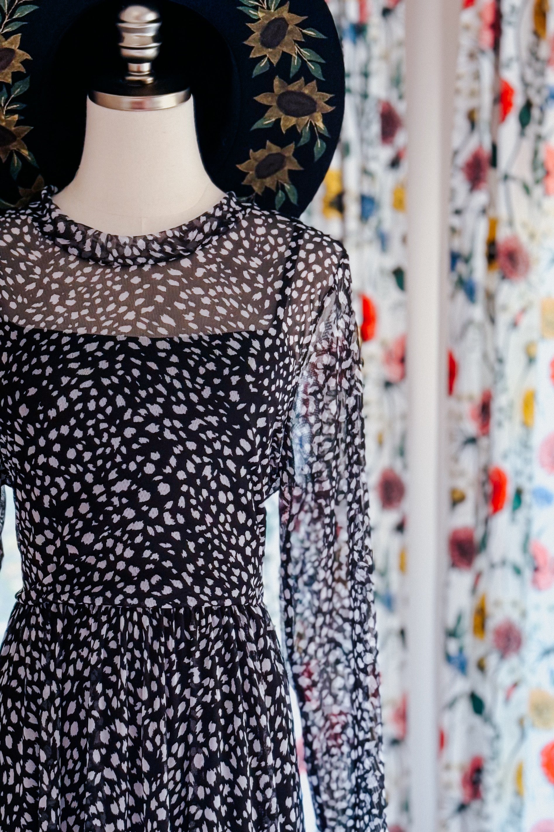 Black Hendrix long sleeve animal print mesh maxi dress on mannequin with ruffled neckline and sheer sleeves indoors
