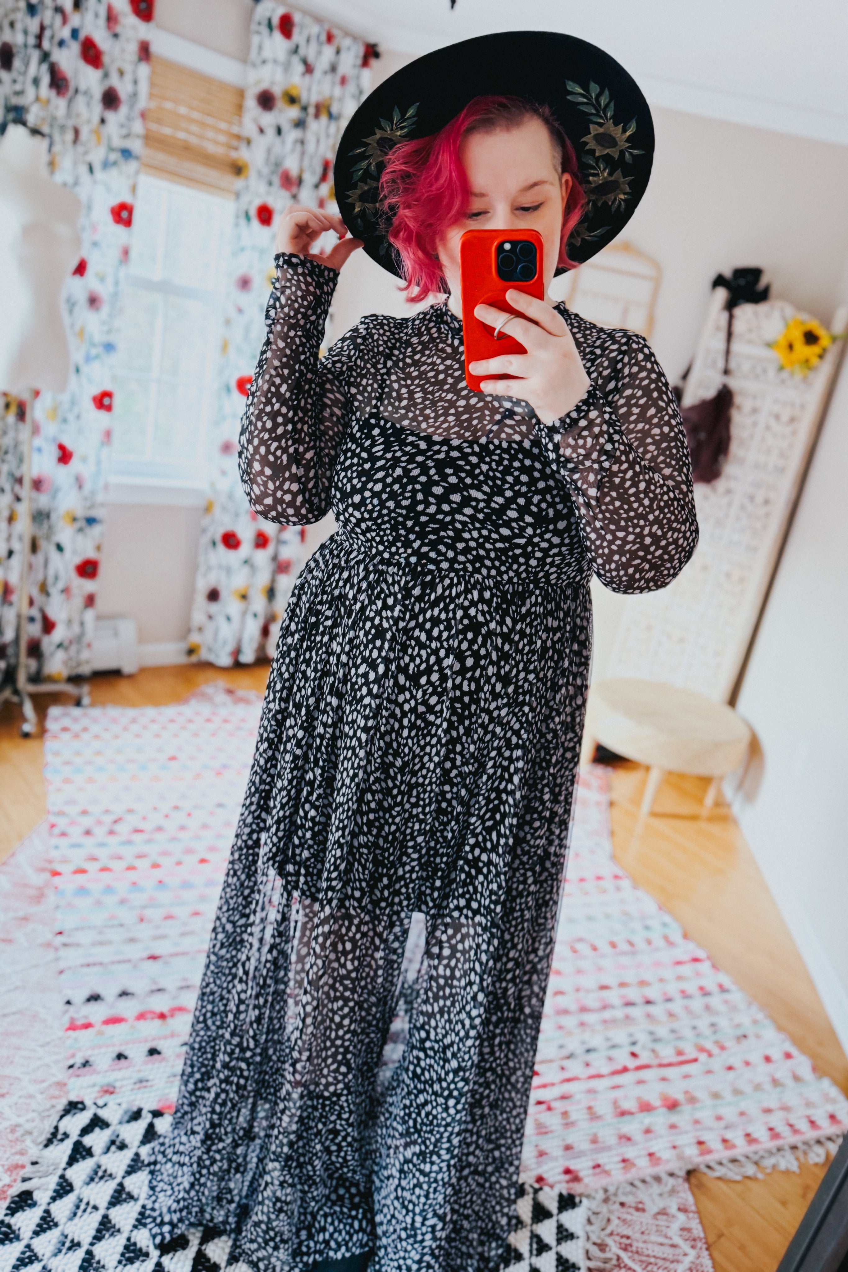 Woman taking mirror selfie wearing black Hendrix long sleeve animal print mesh maxi dress and black wide-brim hat indoors