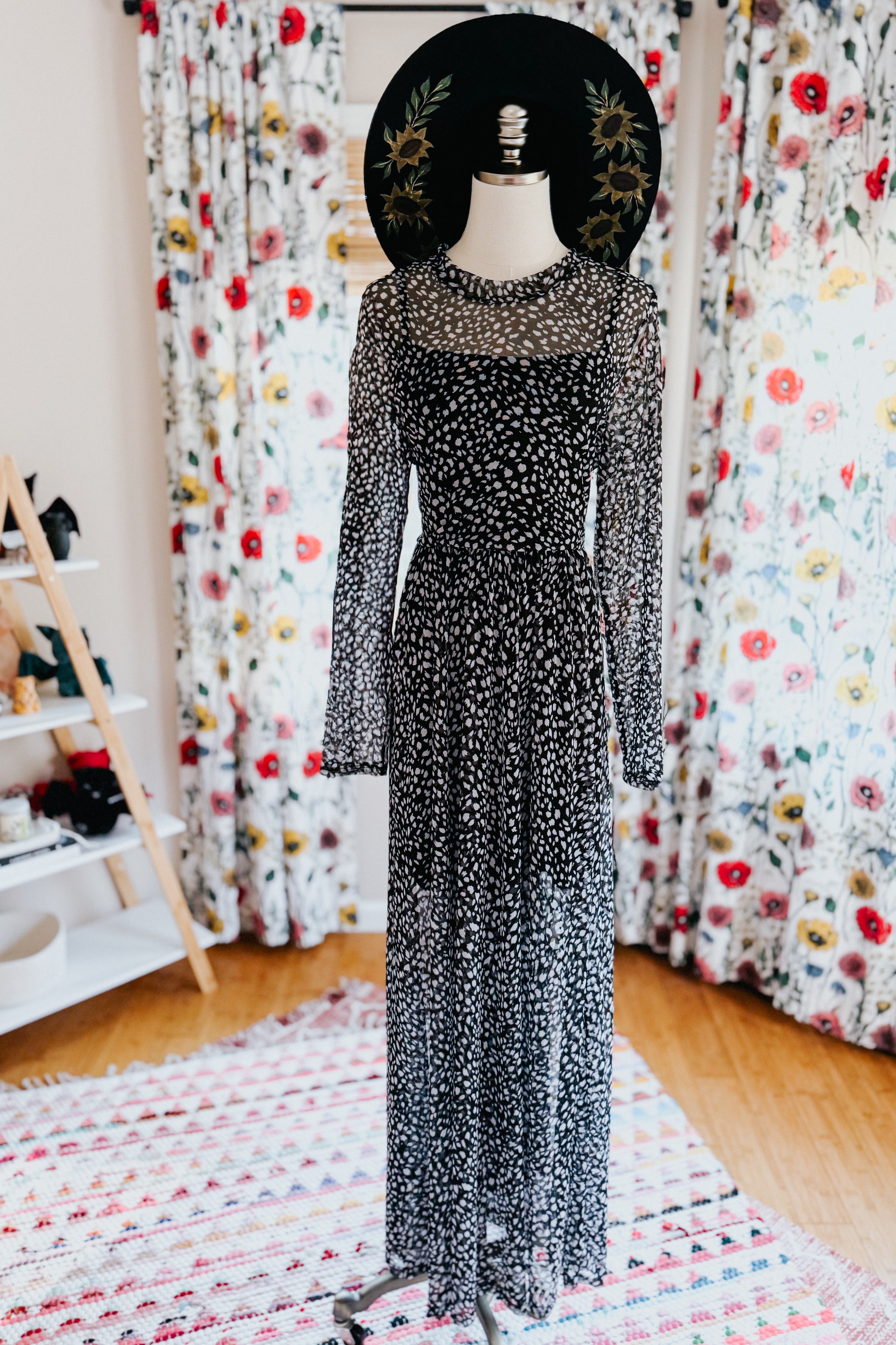 Black Hendrix long sleeve animal print mesh maxi dress displayed on mannequin with embroidered black wide-brim hat indoors