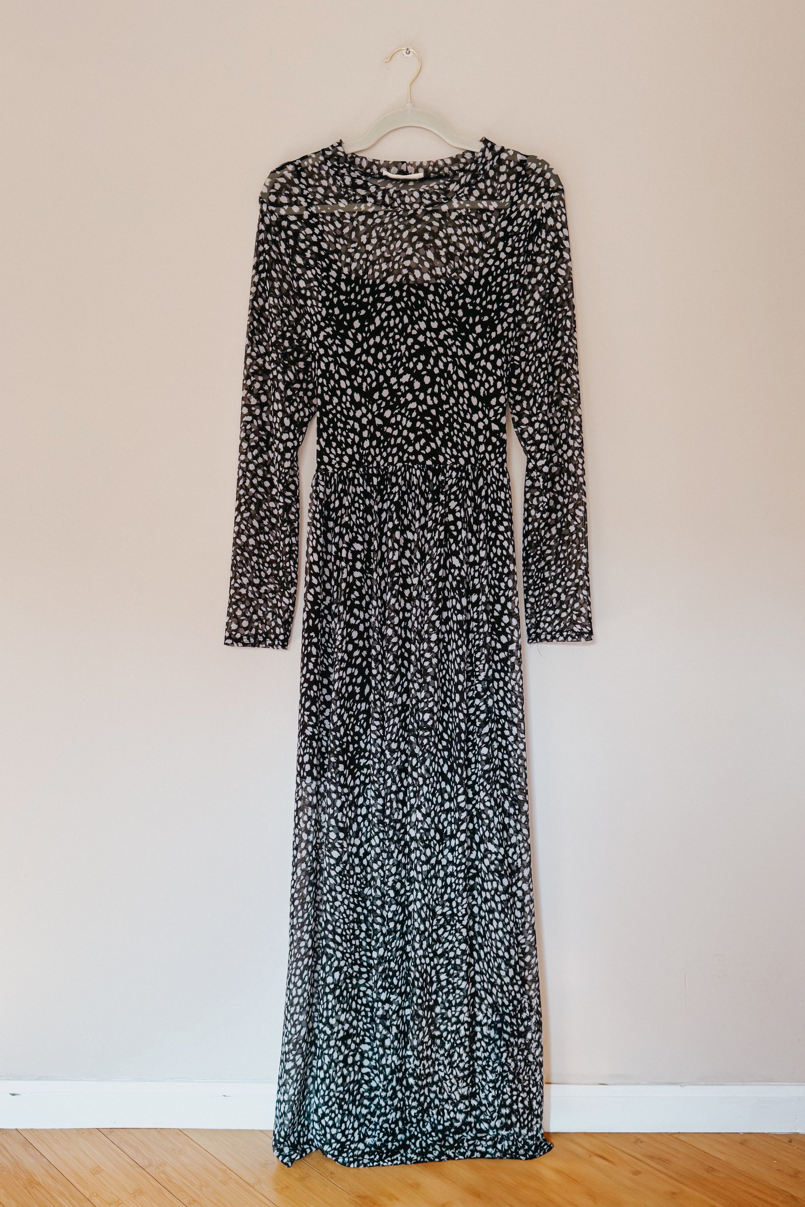 Black Hendrix long sleeve animal print mesh maxi dress hanging on white hanger against beige wall