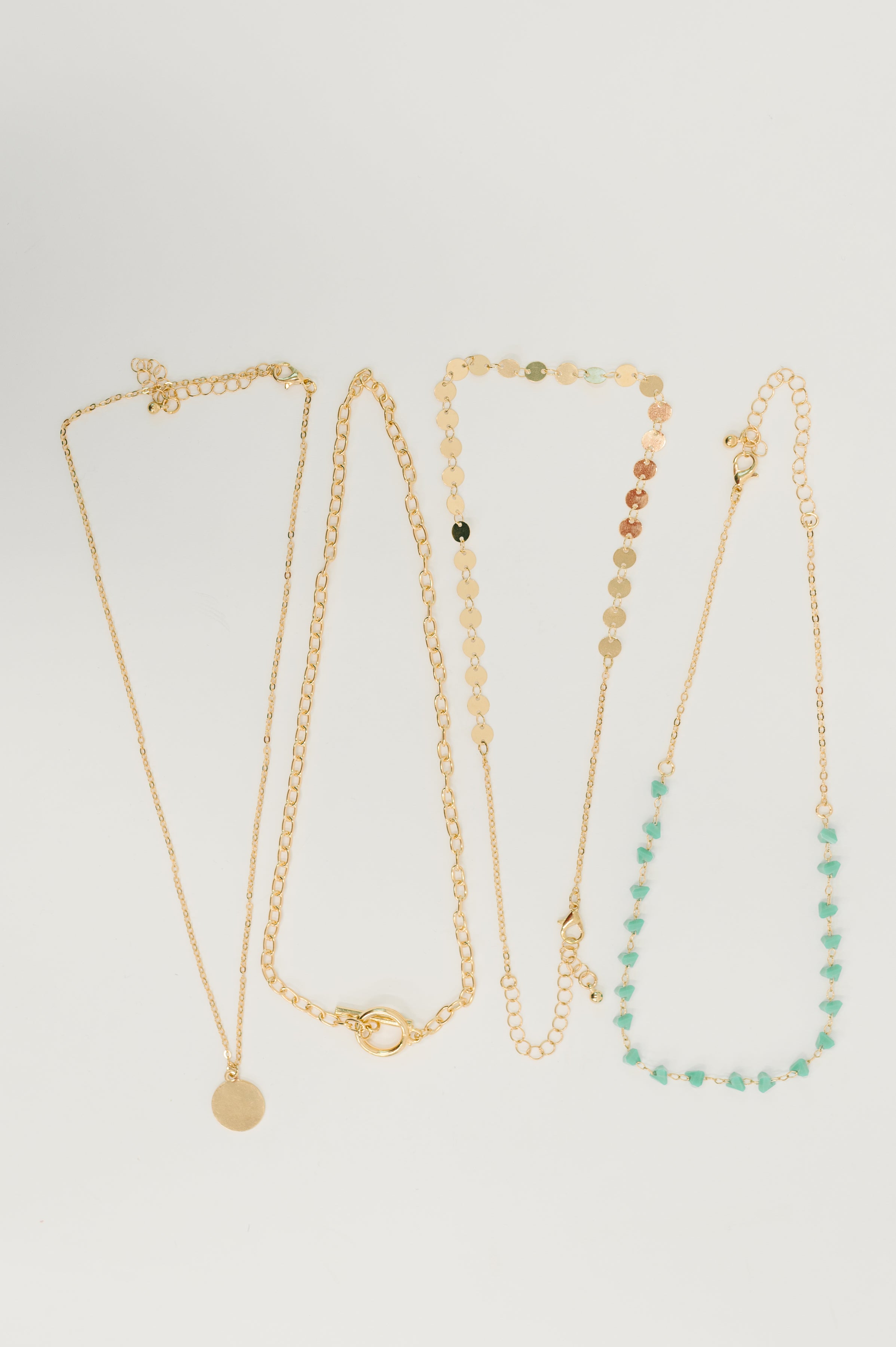 Set of layered boho necklaces with gold chains and turquoise bead accents on white background