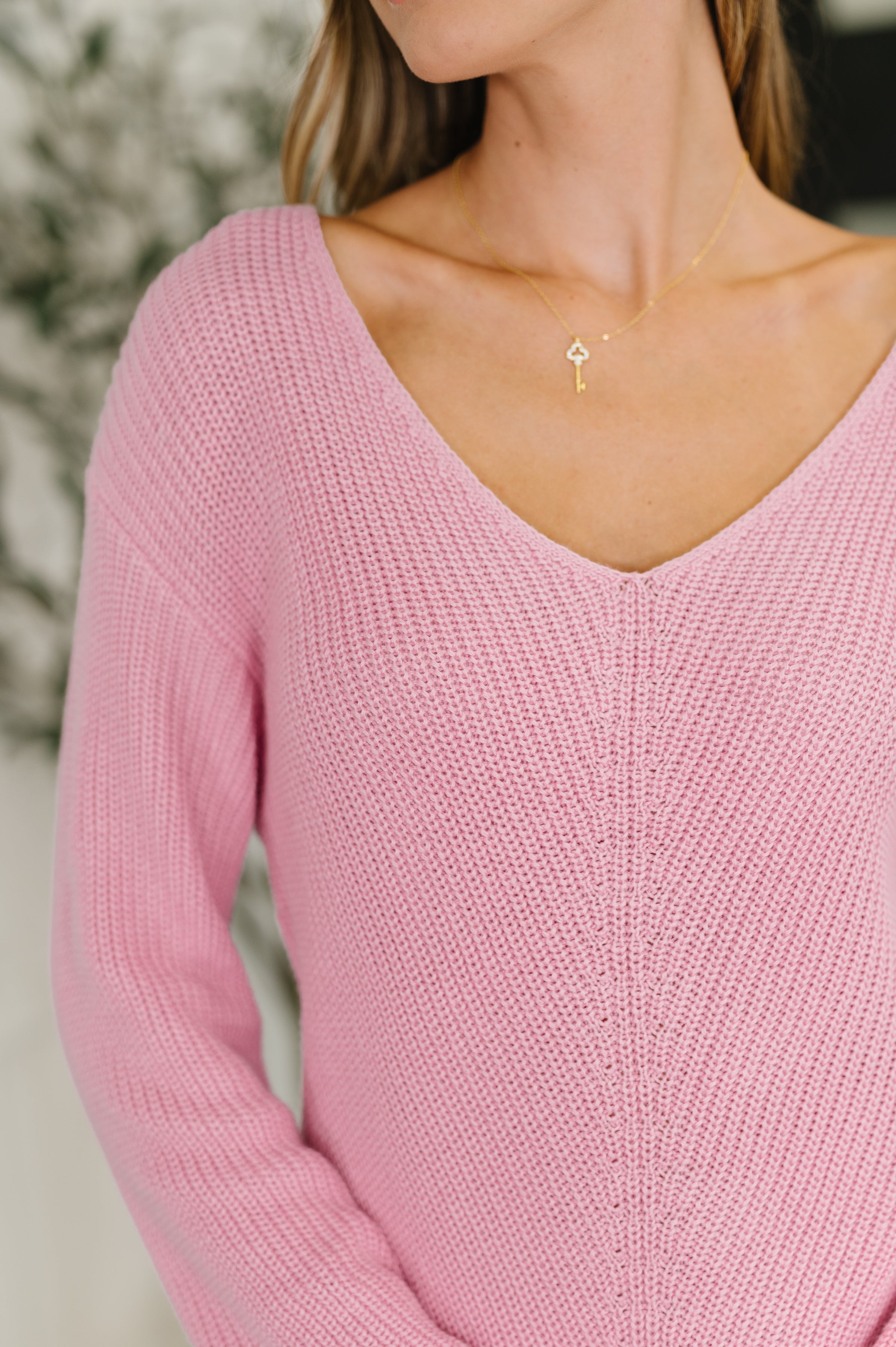 Close-up of woman wearing a pink I'm All Yours V-Neck Sweater featuring textured knit and a delicate gold key necklace