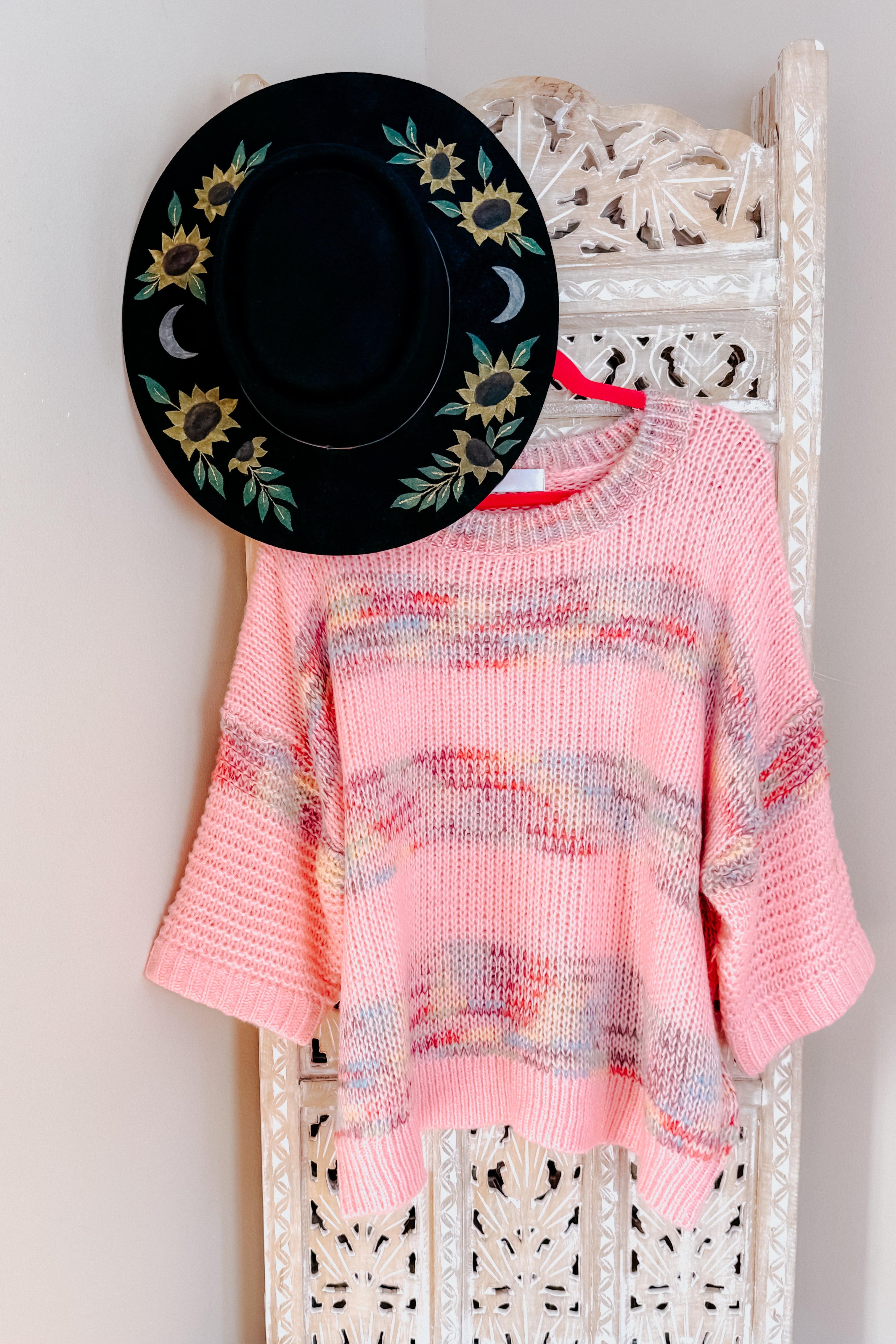 Pink In the Cards Striped Sweater with loose knit and multicolor stripe details displayed on carved wooden hanger