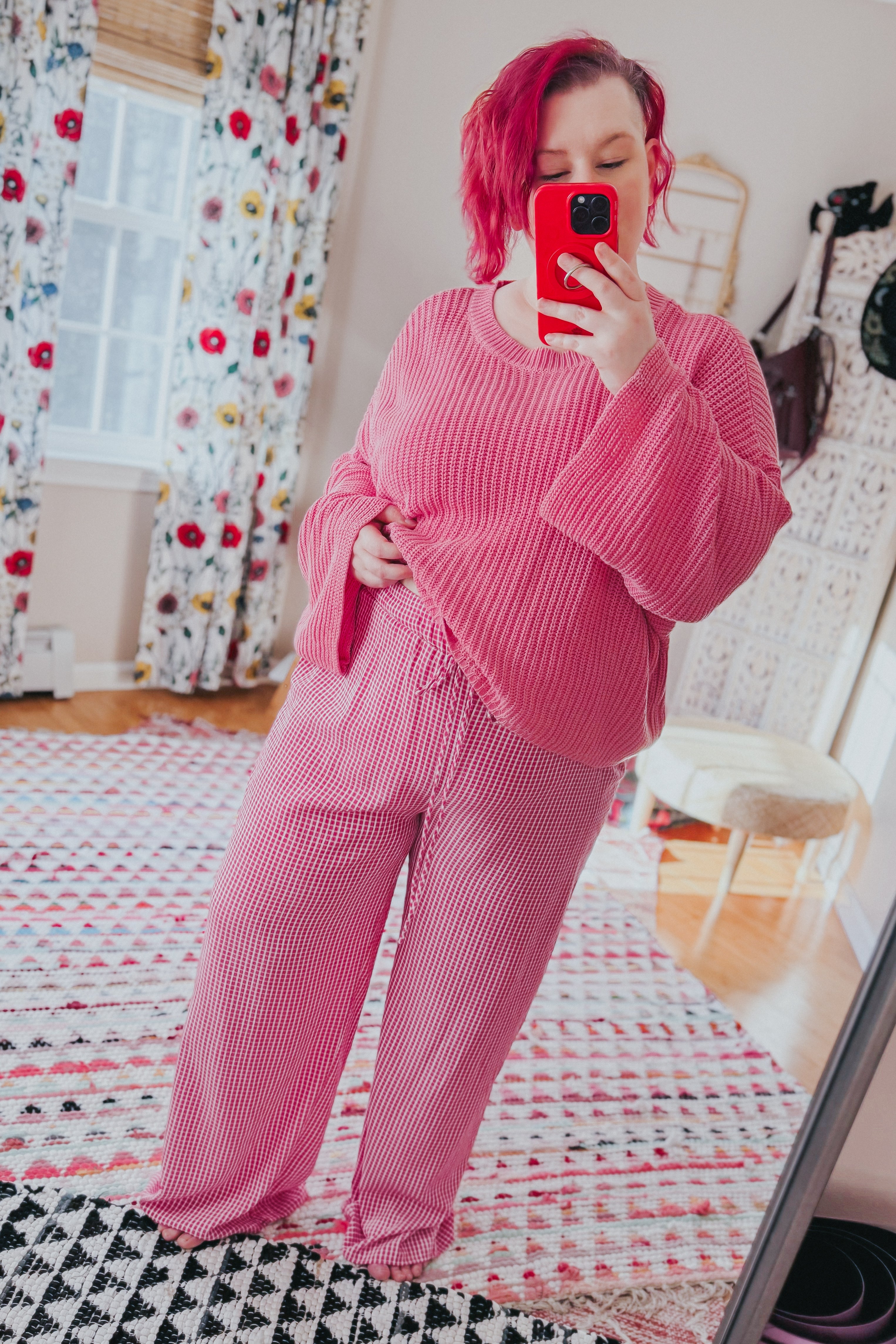 Woman wearing pink In The Groove Checkered Print Pants with drawstring waist paired with loose knit sweater taking mirror selfie indoors