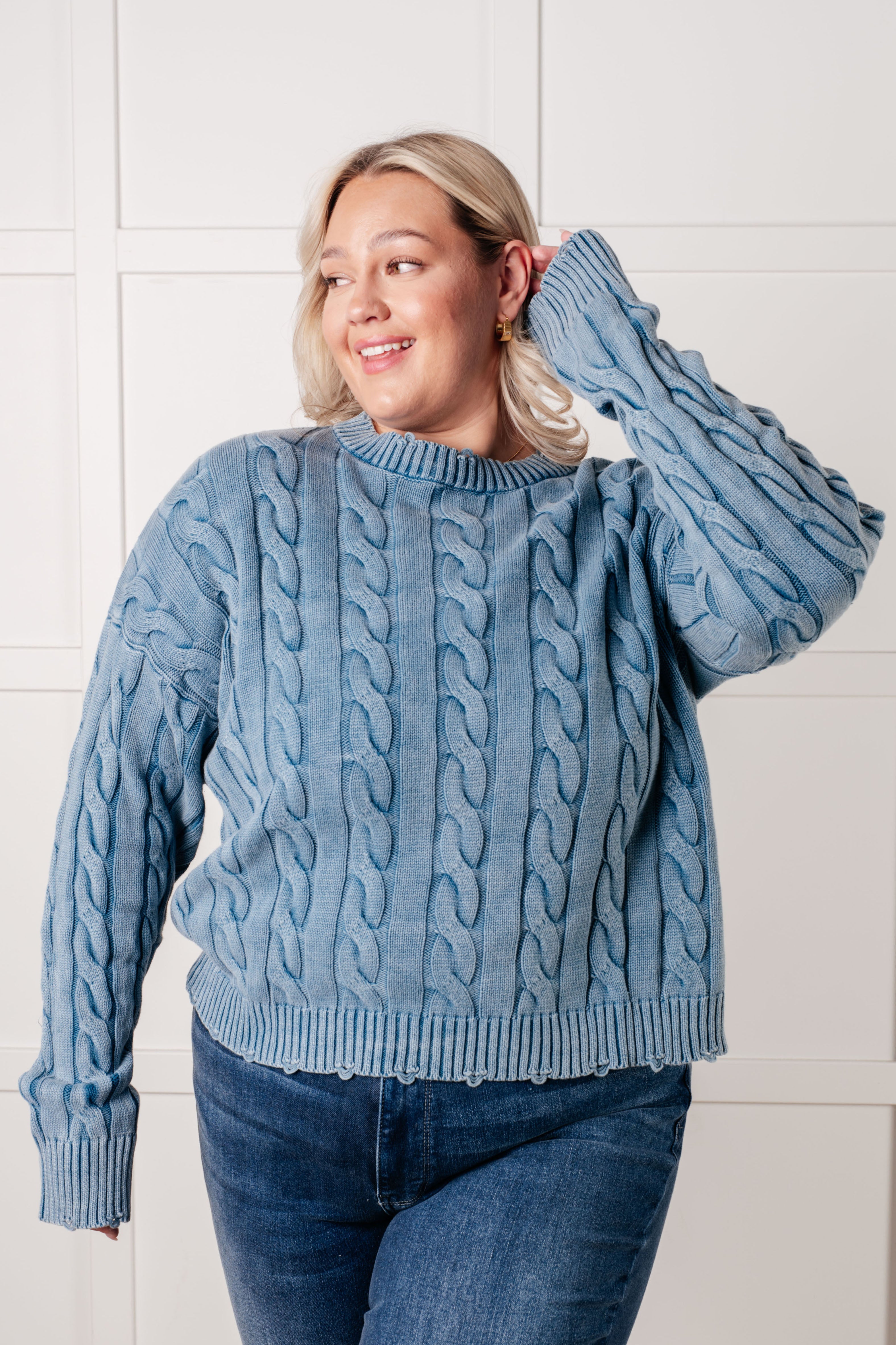 Plus-size woman wearing blue In the Right Direction cable knit sweater with ribbed neckline and hem posing indoors