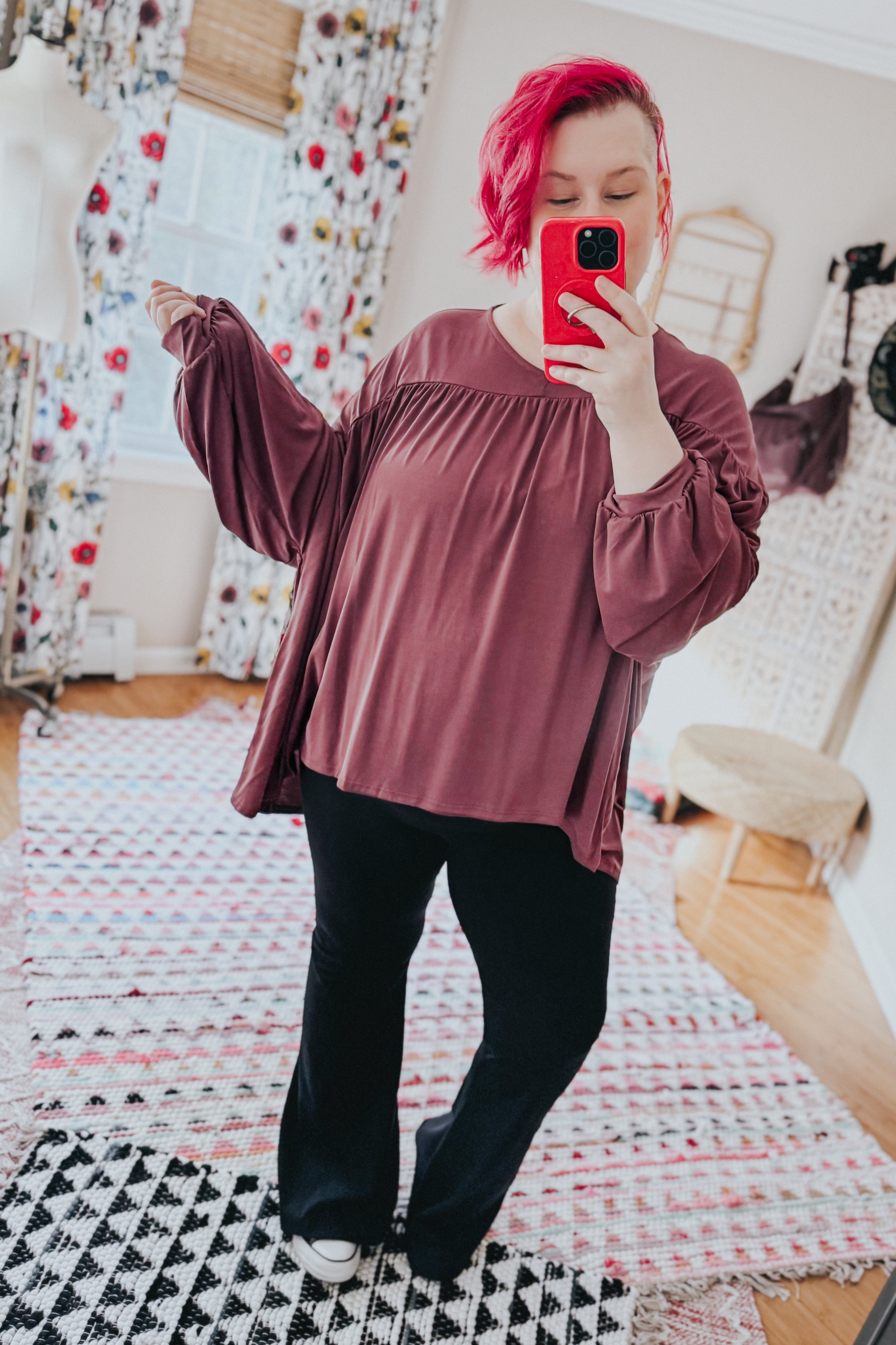 Plus-size woman wearing wine In This Groove modal knit top with gathered yoke and long loose sleeves taking selfie indoors