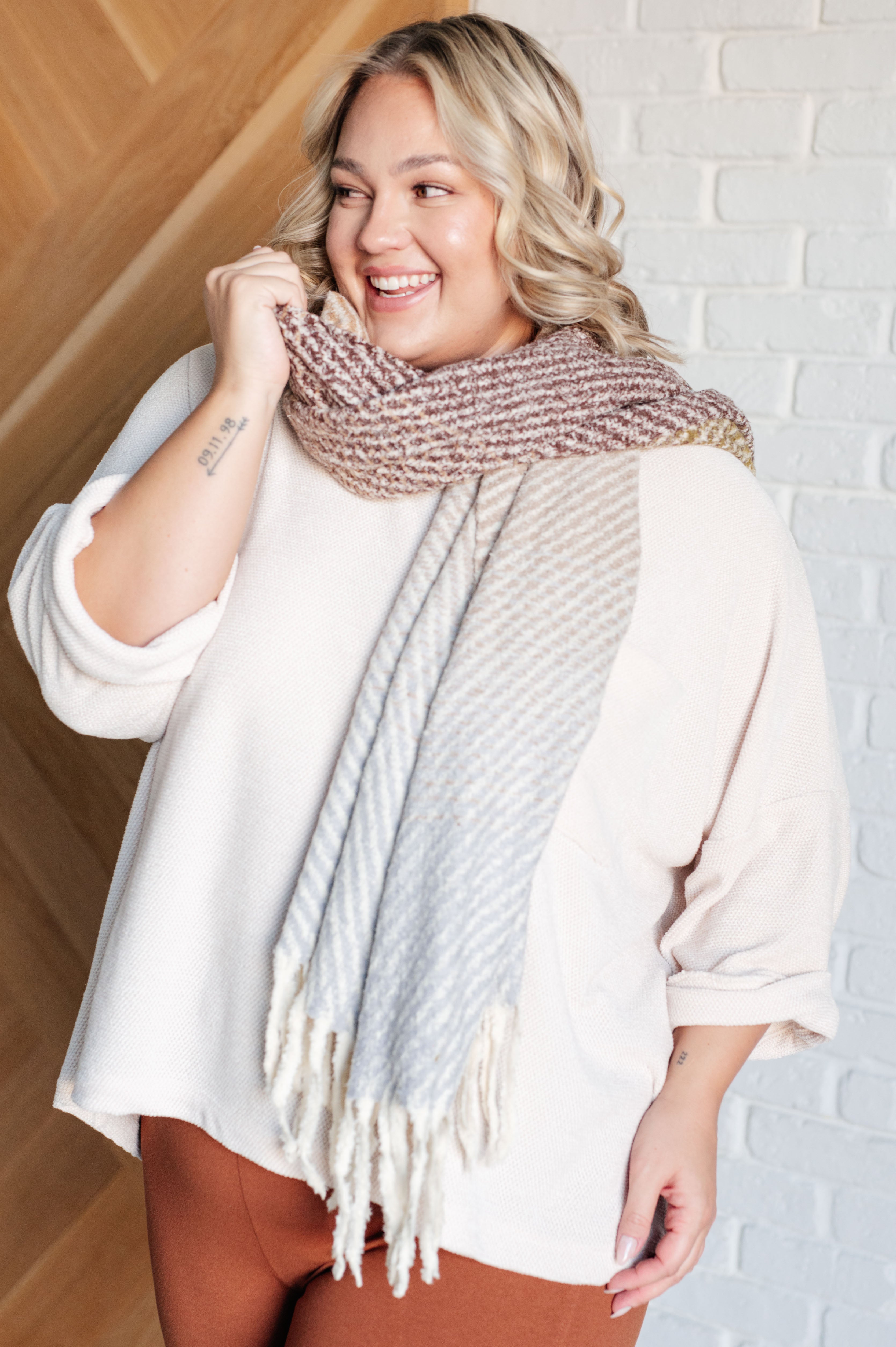 Smiling person wearing oversized ivory Thoughts chenille blouse with rolled sleeves and cozy knit scarf indoors
