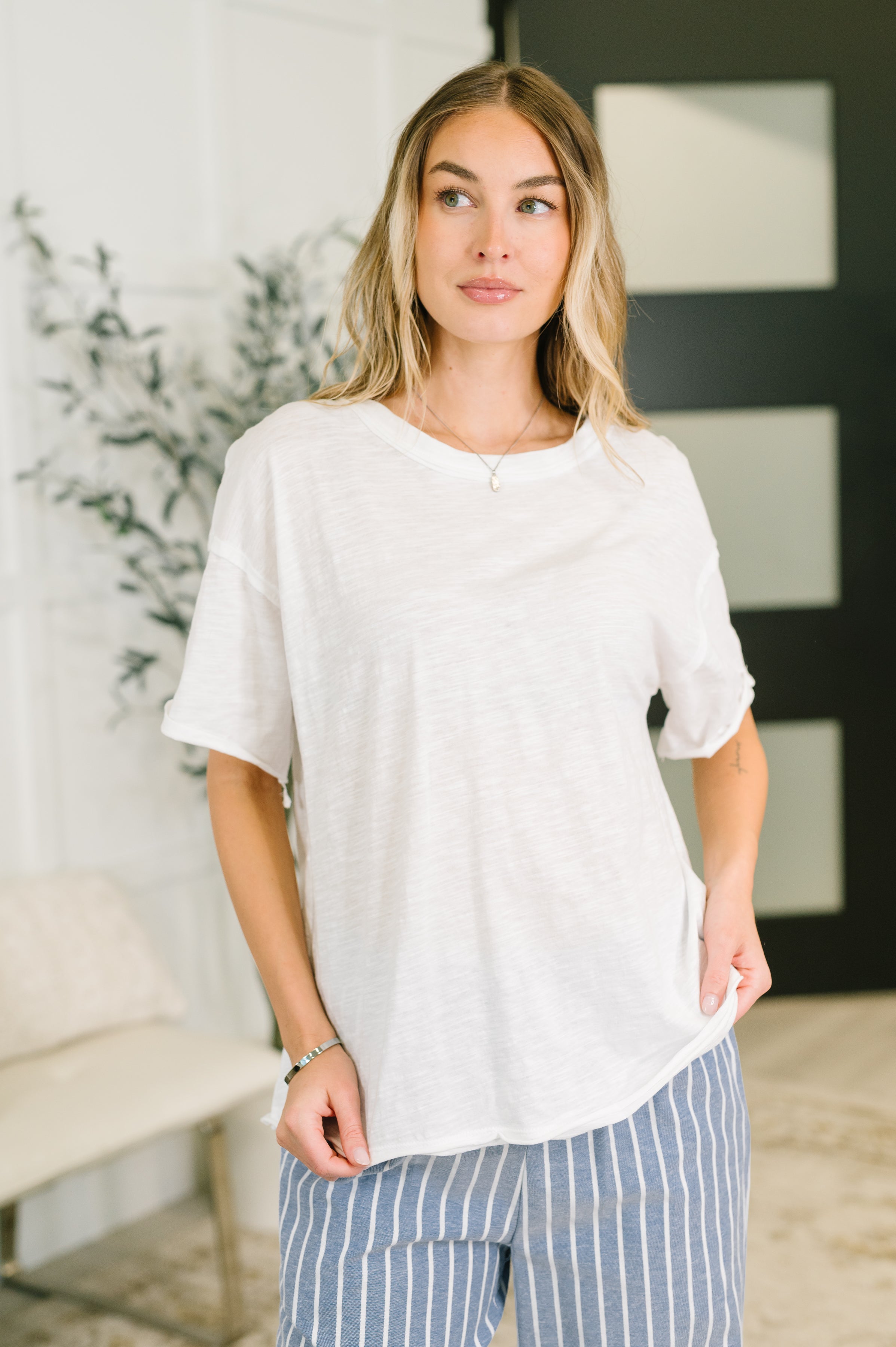 Woman wearing relaxed ivory tee paired with blue and white striped pants in soft natural indoor setting