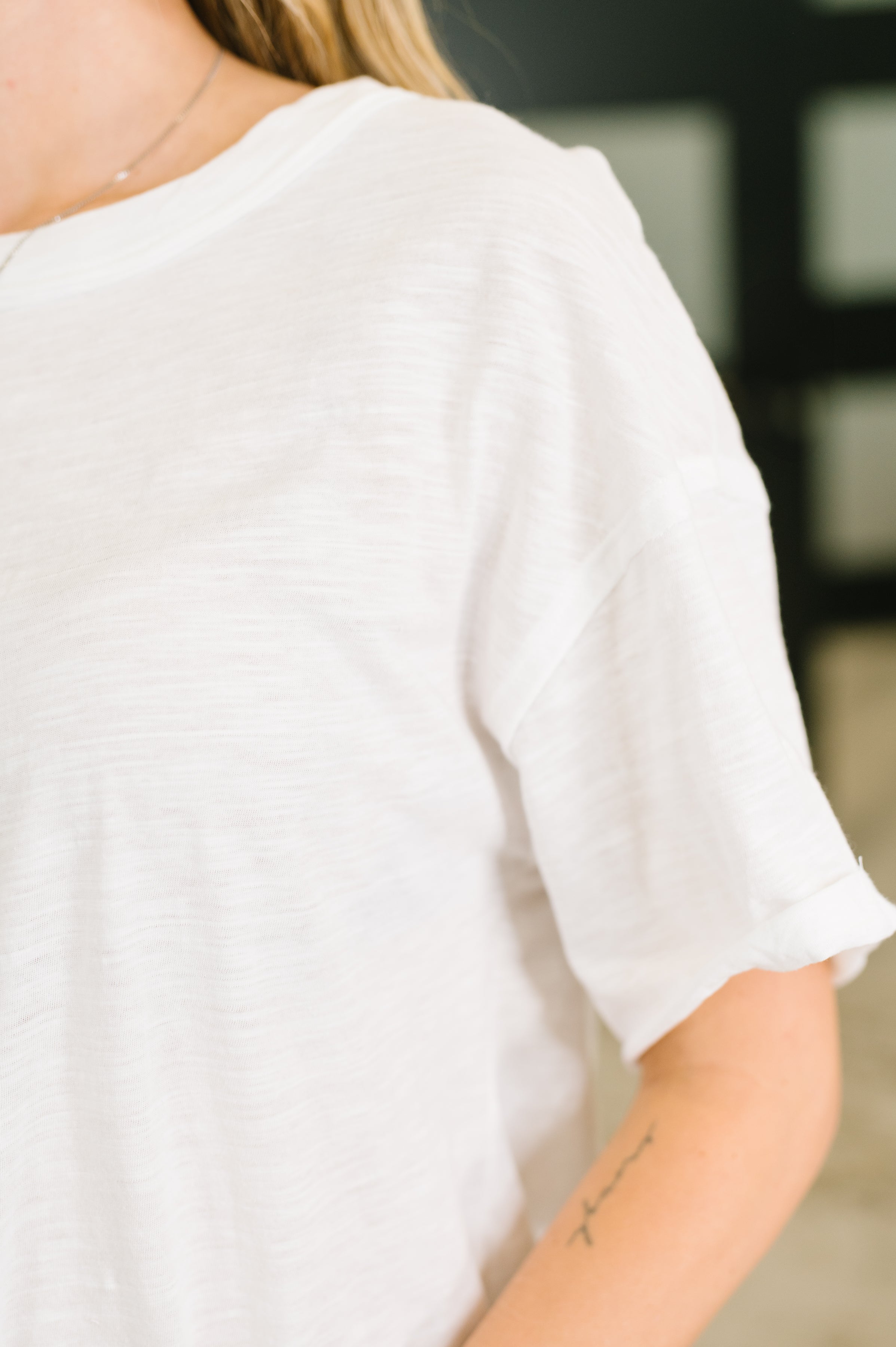 Close-up of a relaxed ivory tee with rolled sleeves worn by a woman showing soft fabric texture and casual style