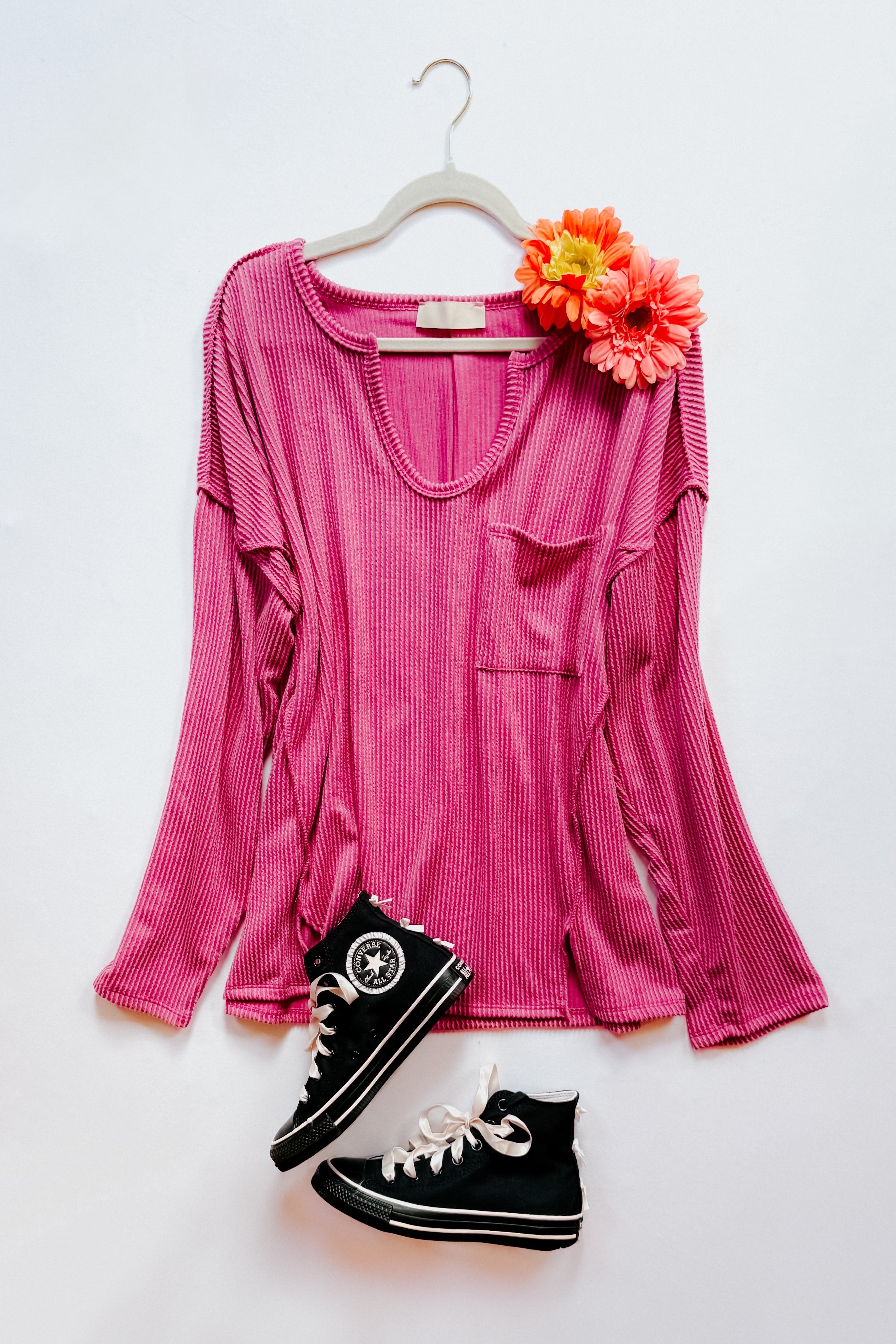 Magenta ribbed long sleeve top with front pocket displayed with black high-top sneakers and orange flowers