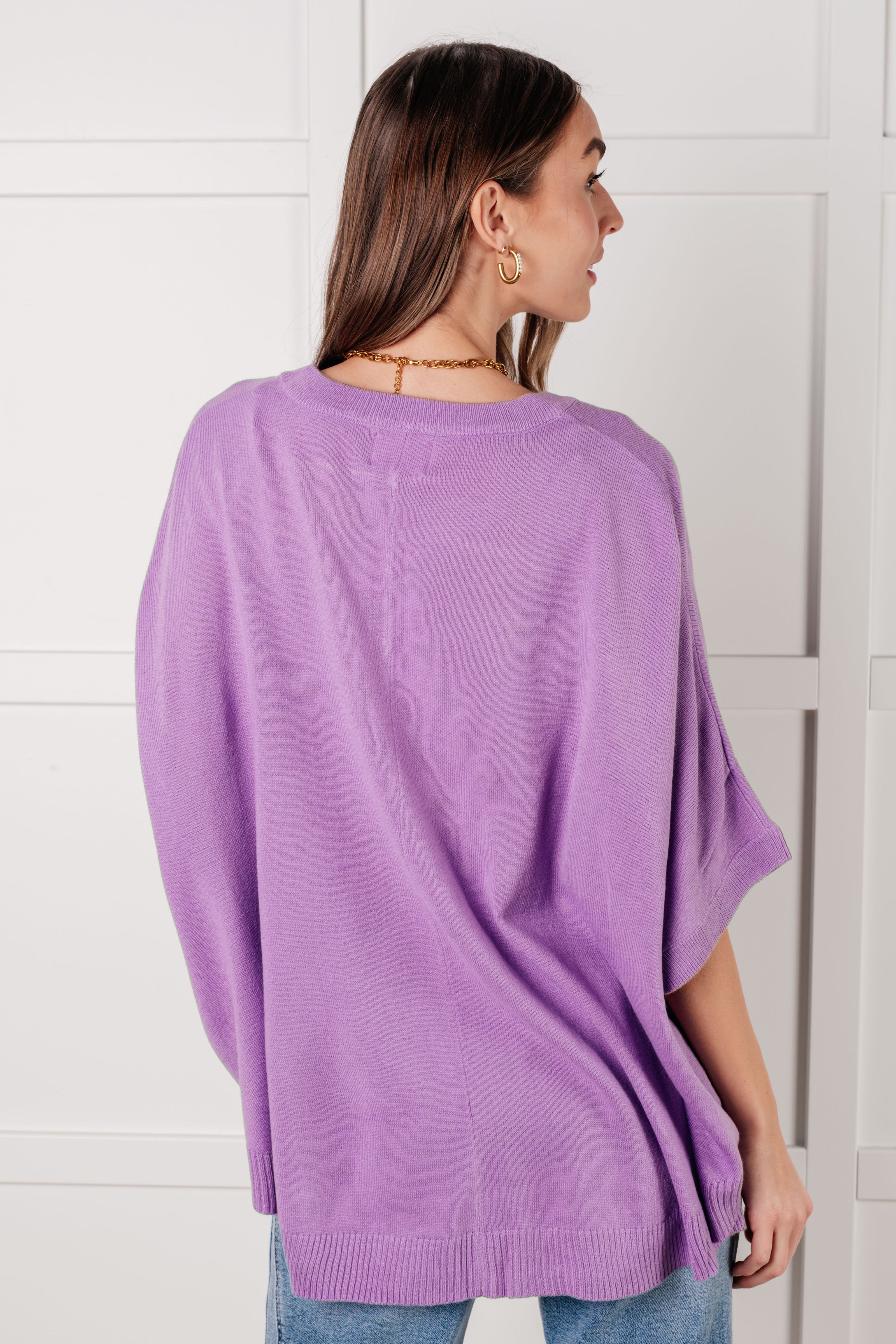 Woman shown from behind wearing a soft lilac relaxed fit top with dolman sleeves and ribbed hem standing indoors