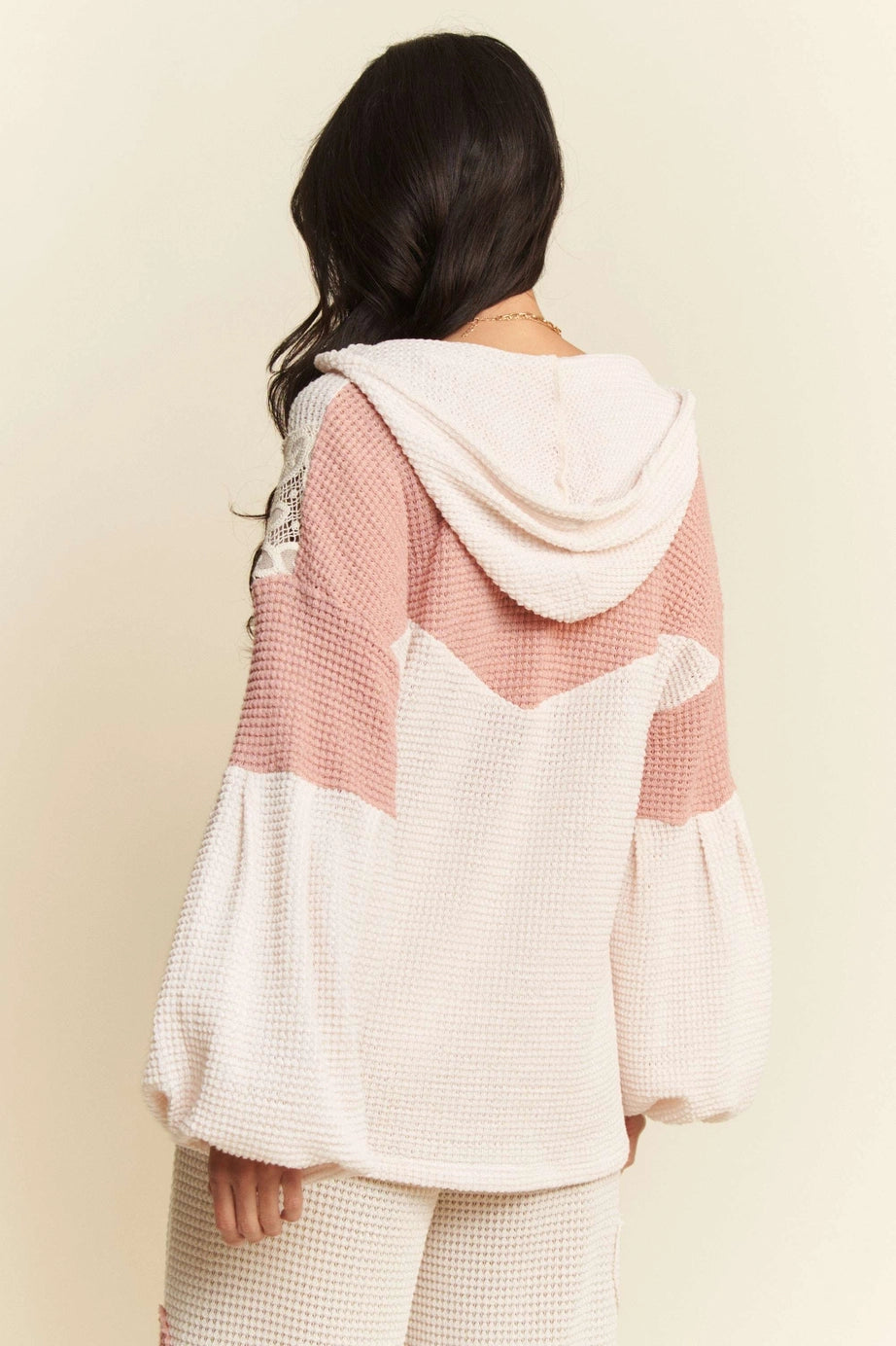 Woman wearing cream and soft pink waffle knit hooded top with balloon sleeves shown from back