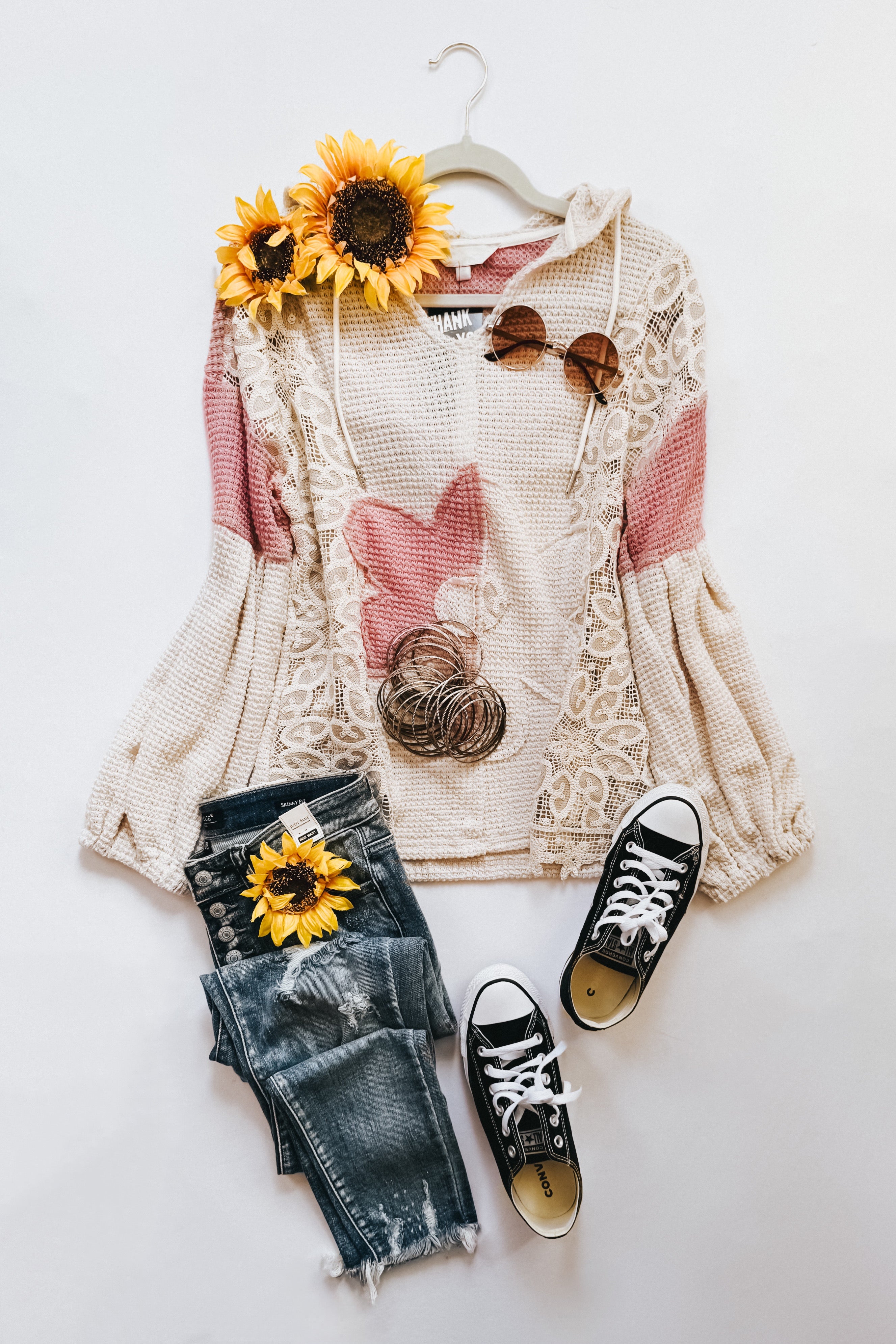 Cream waffle knit hooded top with balloon sleeves and lace trim paired with distressed dark jeans and black sneakers