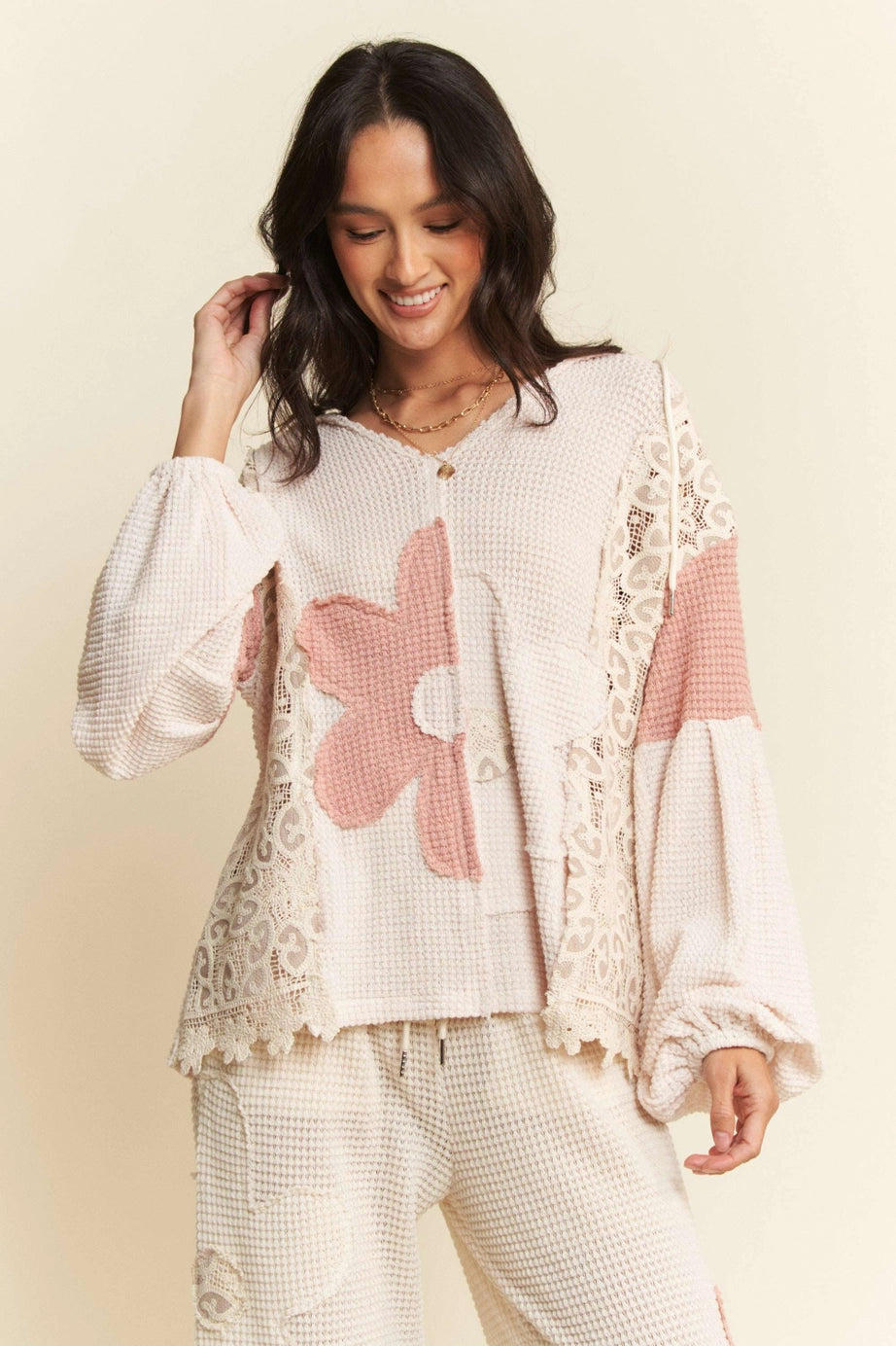 Cream waffle knit top with pink floral and lace panel accents worn by smiling woman with dark hair
