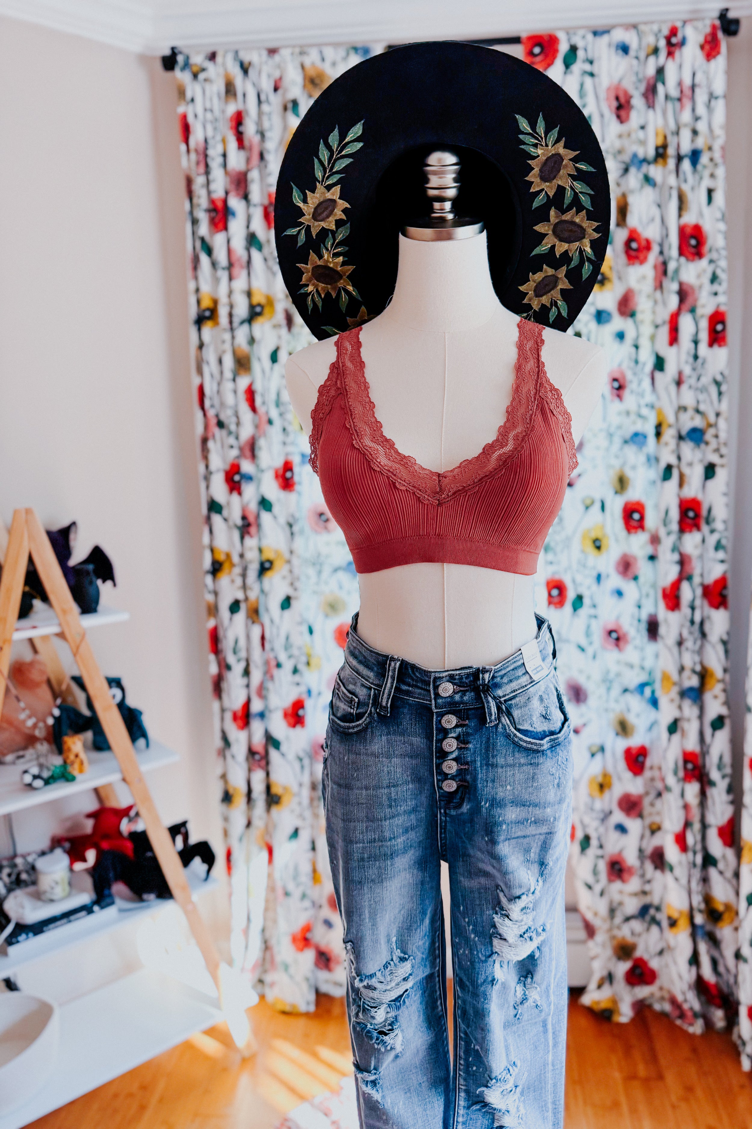 Rust ribbed bralette with lace trim paired with high-waisted distressed blue jeans on mannequin indoors