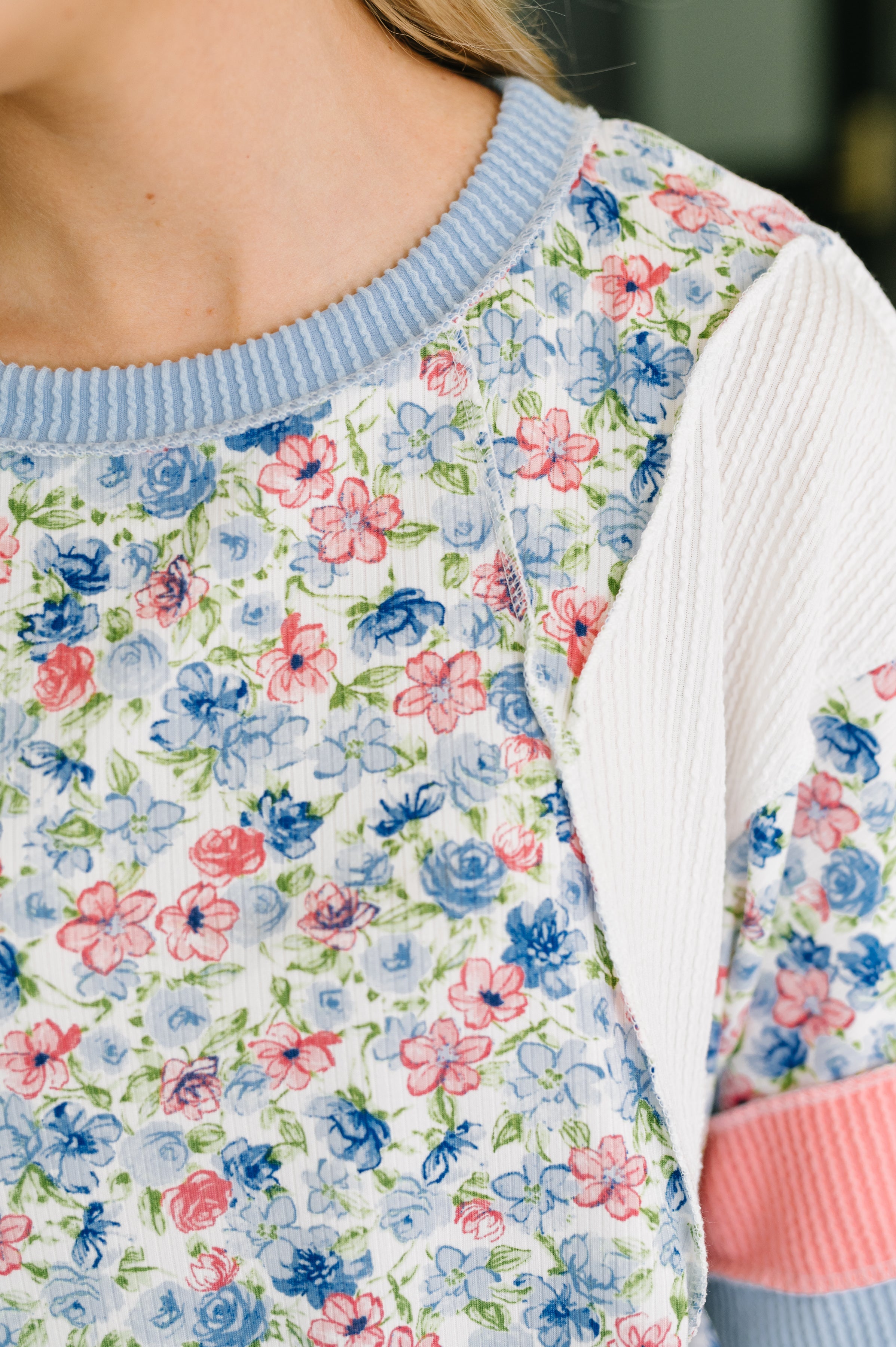 Close-up of floral ribbed knit top with blue banded neckline and white and pink color block sleeve detail