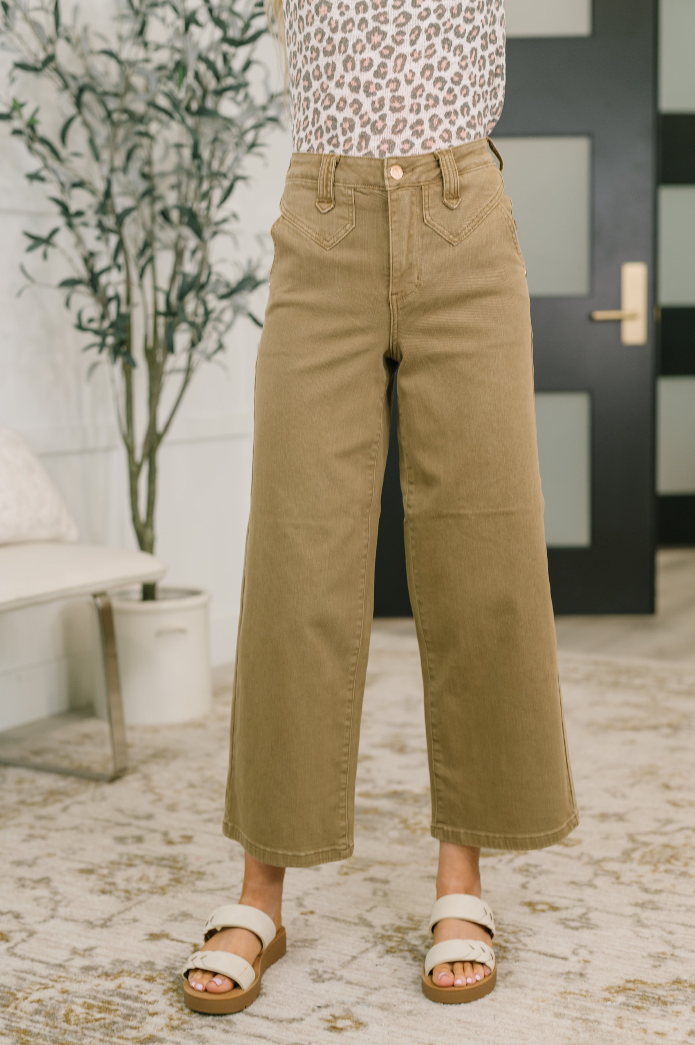 Woman wearing high-waist brown wide-leg ankle jeans with vintage yoke paired with white sandals indoors