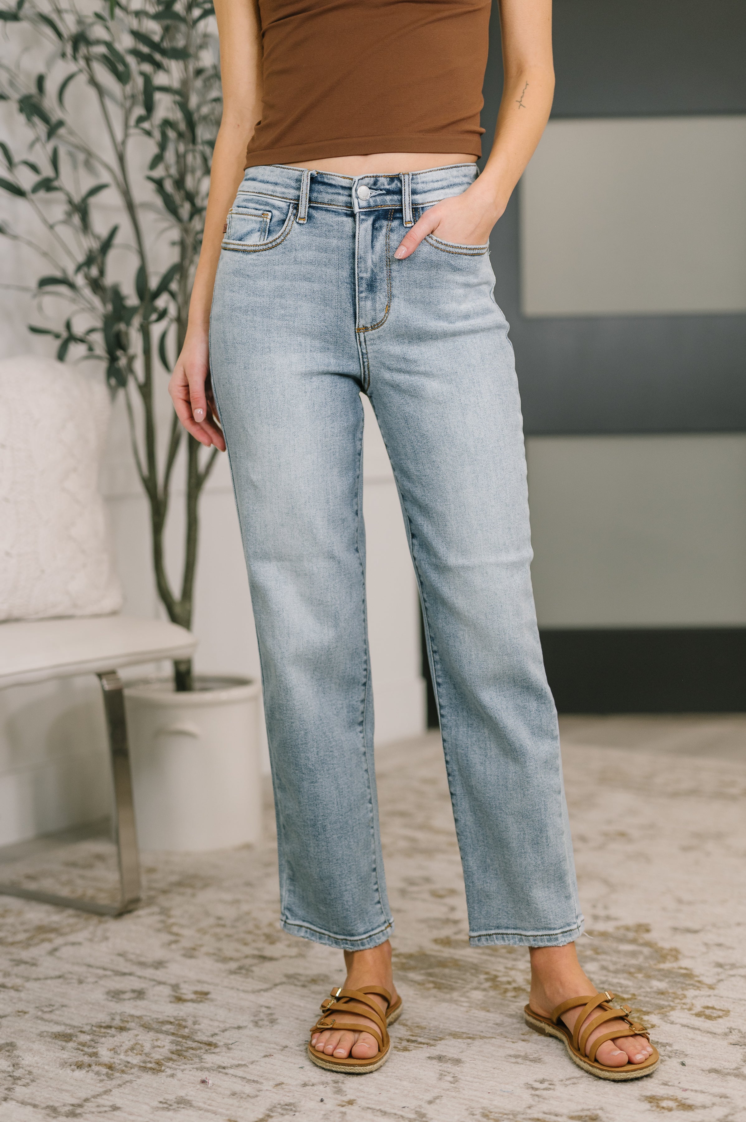 Front view of woman wearing light blue Natalie High Waist Ankle Straight Jeans paired with tan sandals indoors