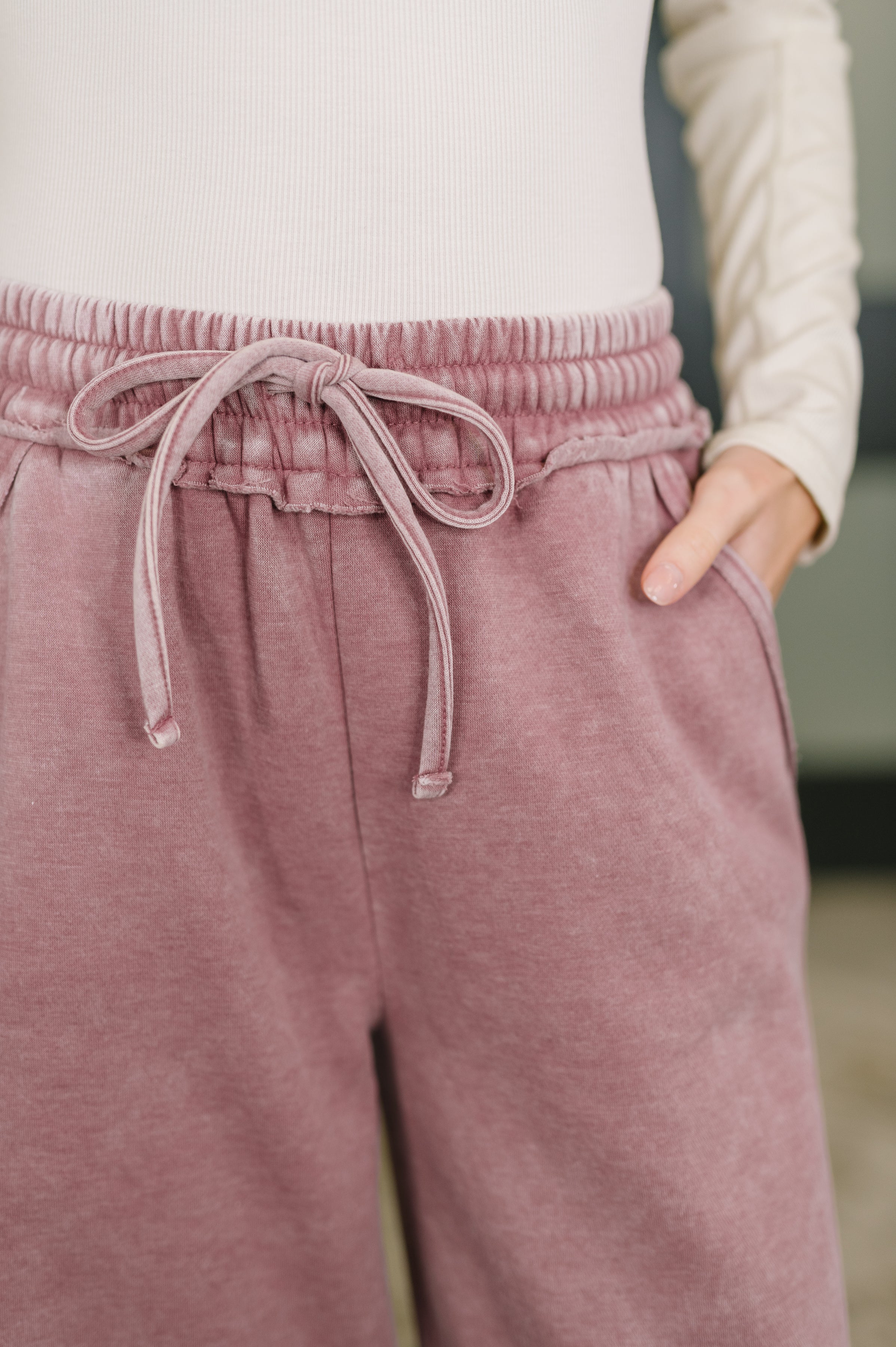 Close-up of light rose high waist palazzo sweatpants with drawstring waist and side pockets worn with cream ribbed top