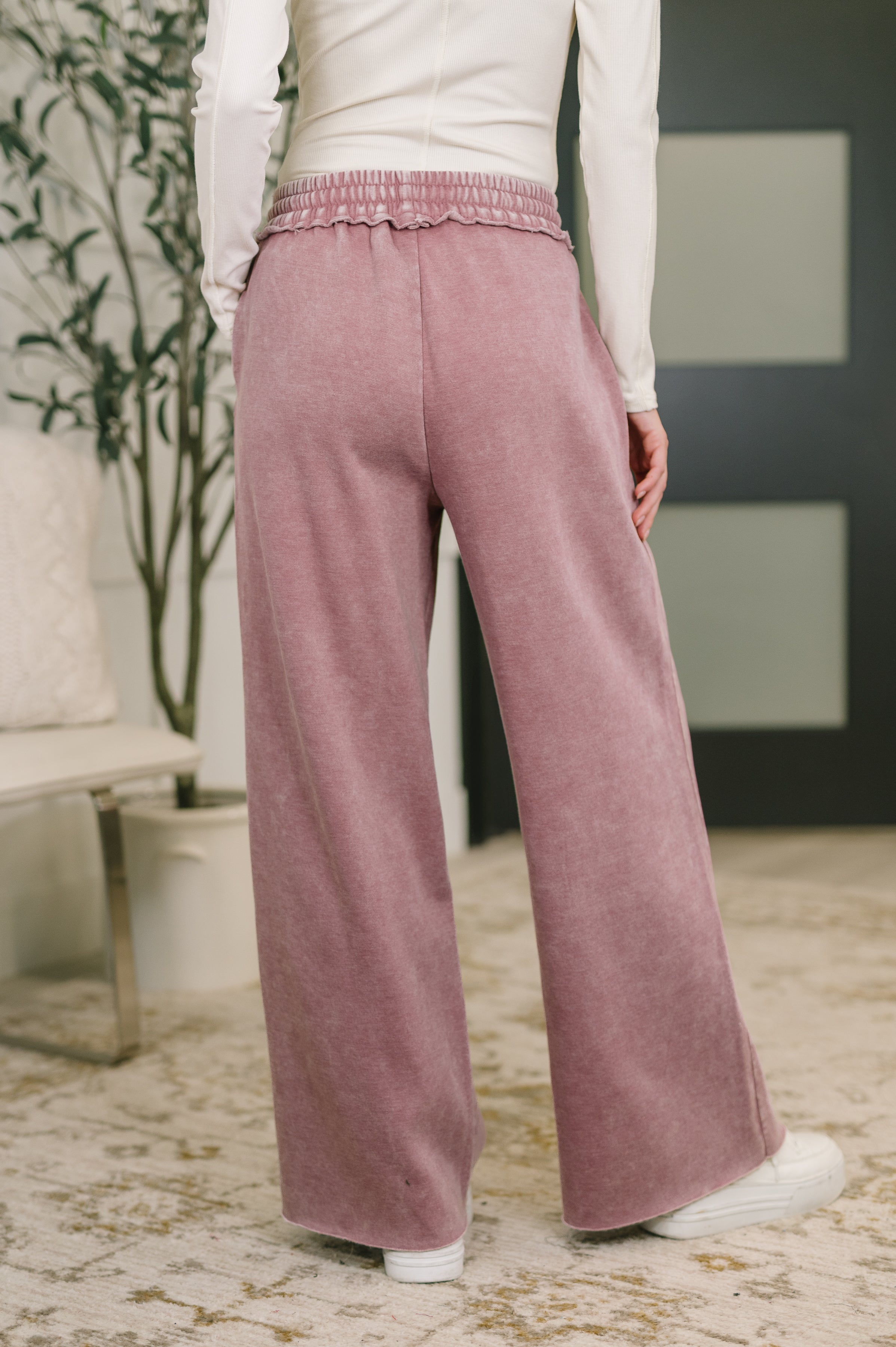 Rear view of woman indoors wearing light rose high waist wide-leg palazzo sweatpants with elastic waistband