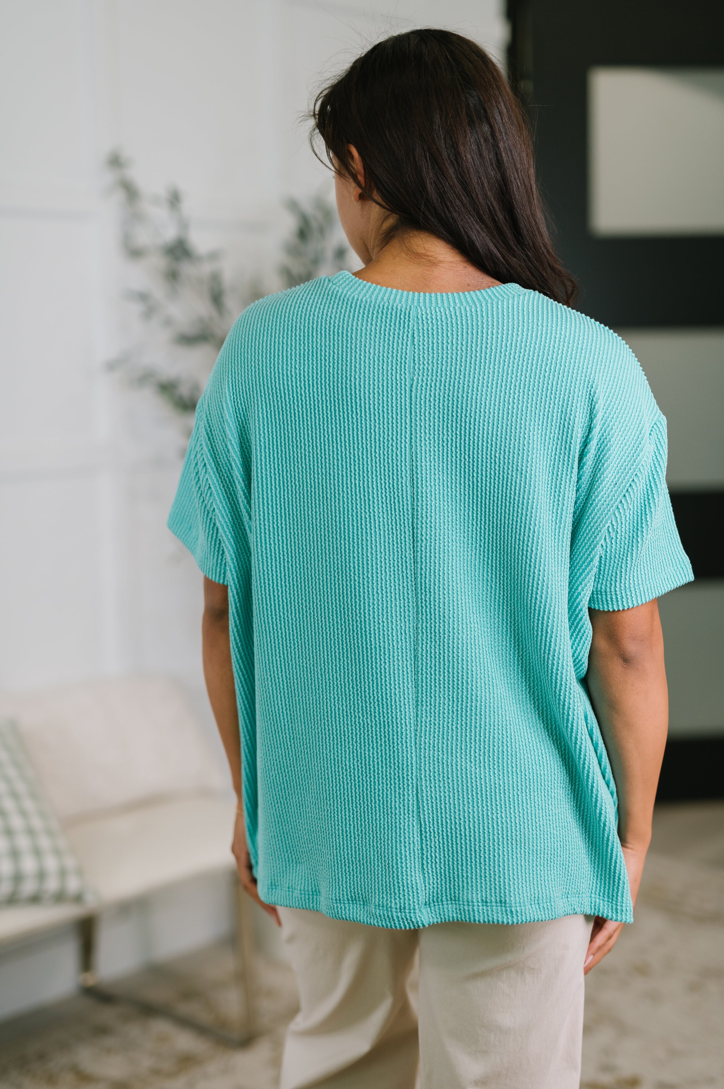 Back view of person wearing turquoise textured boxy tee with short sleeves and relaxed fit indoors