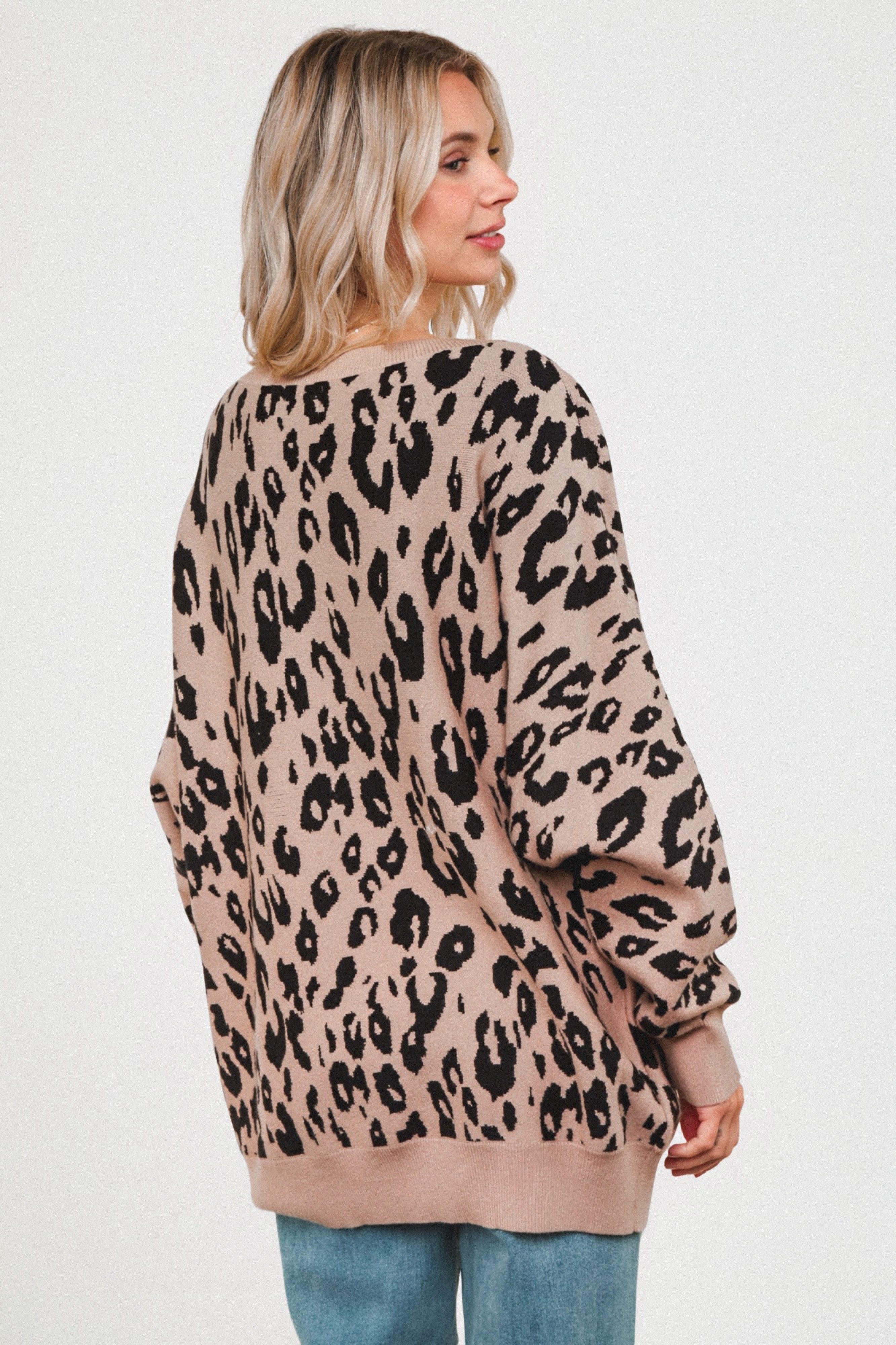 Woman shown from behind wearing a mocha leopard print sweater with a relaxed fit and ribbed cuffs, paired with light blue jeans.