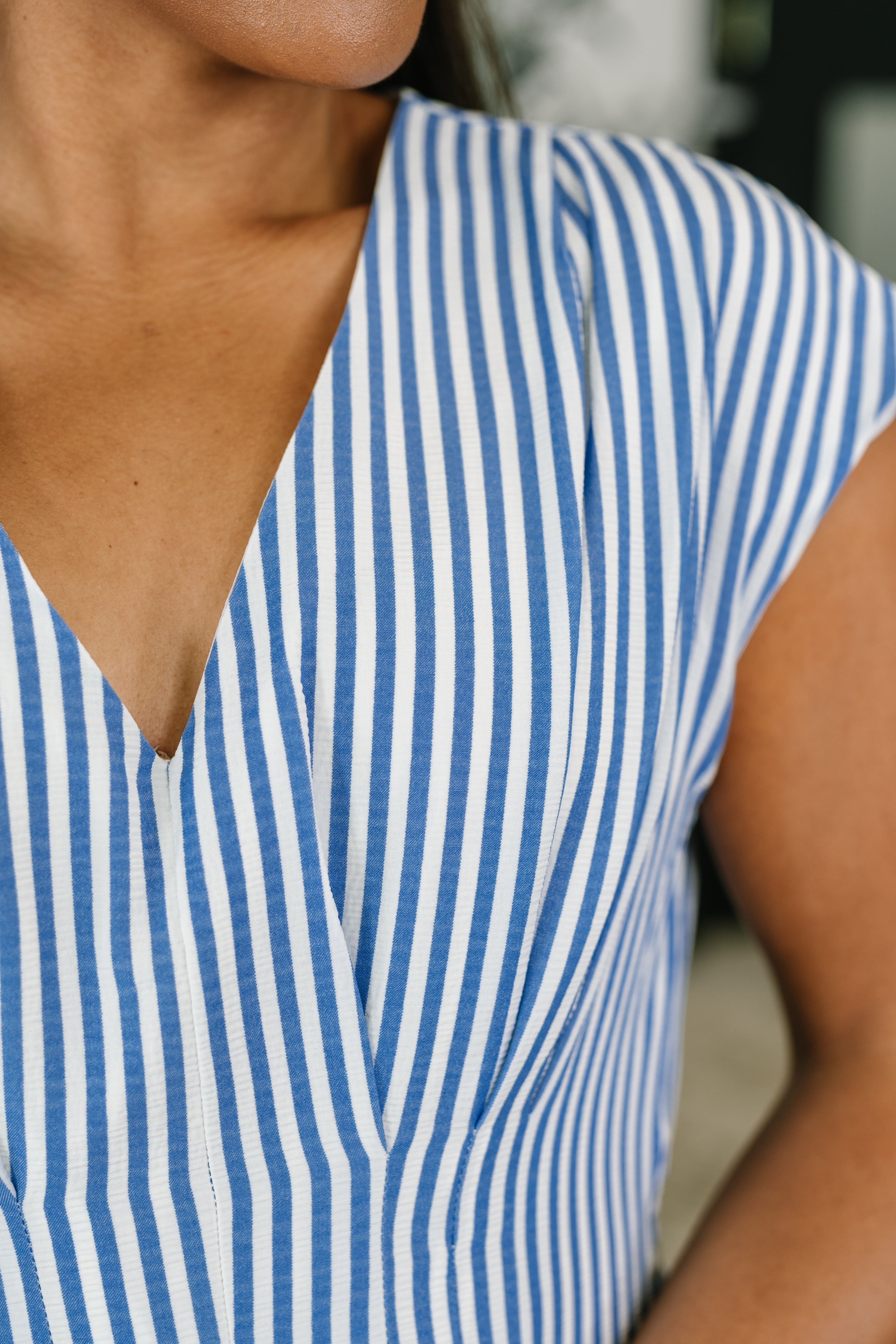 Close-up of V-neck dress with blue and white vertical stripes and cap sleeve in eclectic, free-spirited style