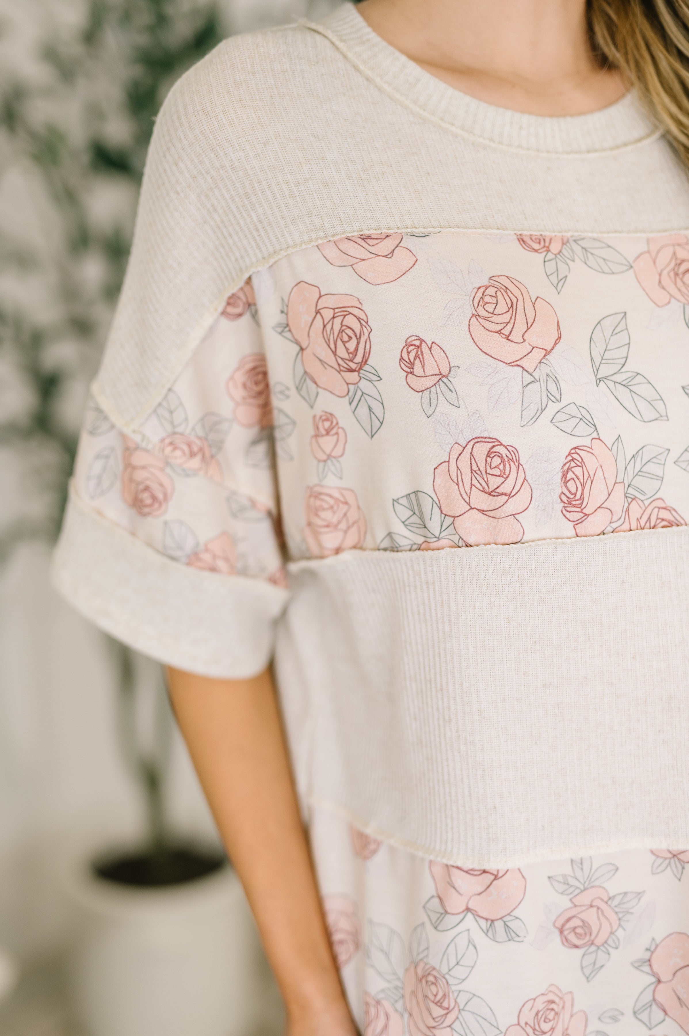 Close-up of pink floral color block relaxed top with ribbed knit and rolled half sleeves worn indoors
