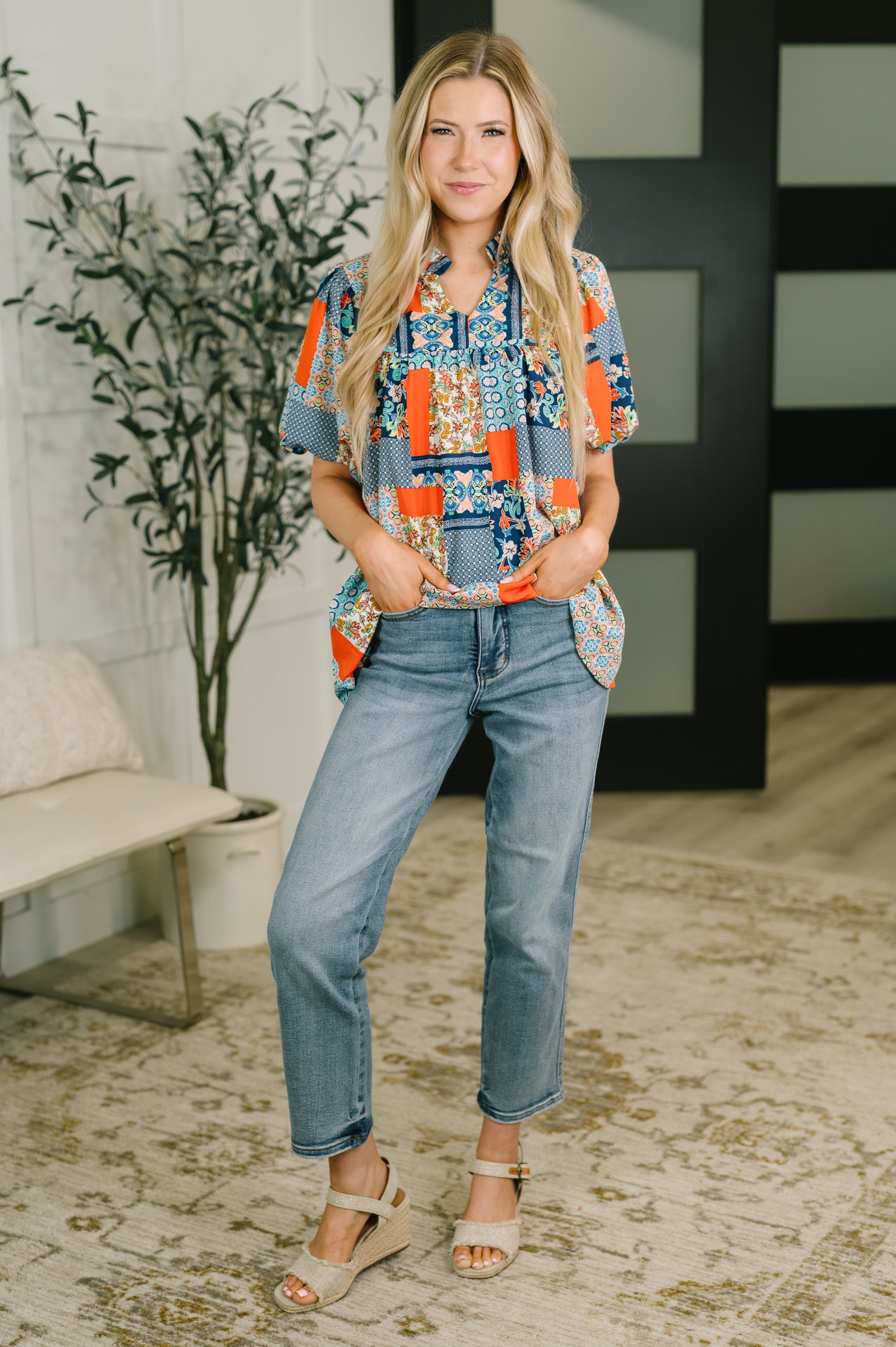 Woman wearing a blue patchwork blouse with puff sleeves and jeans indoors