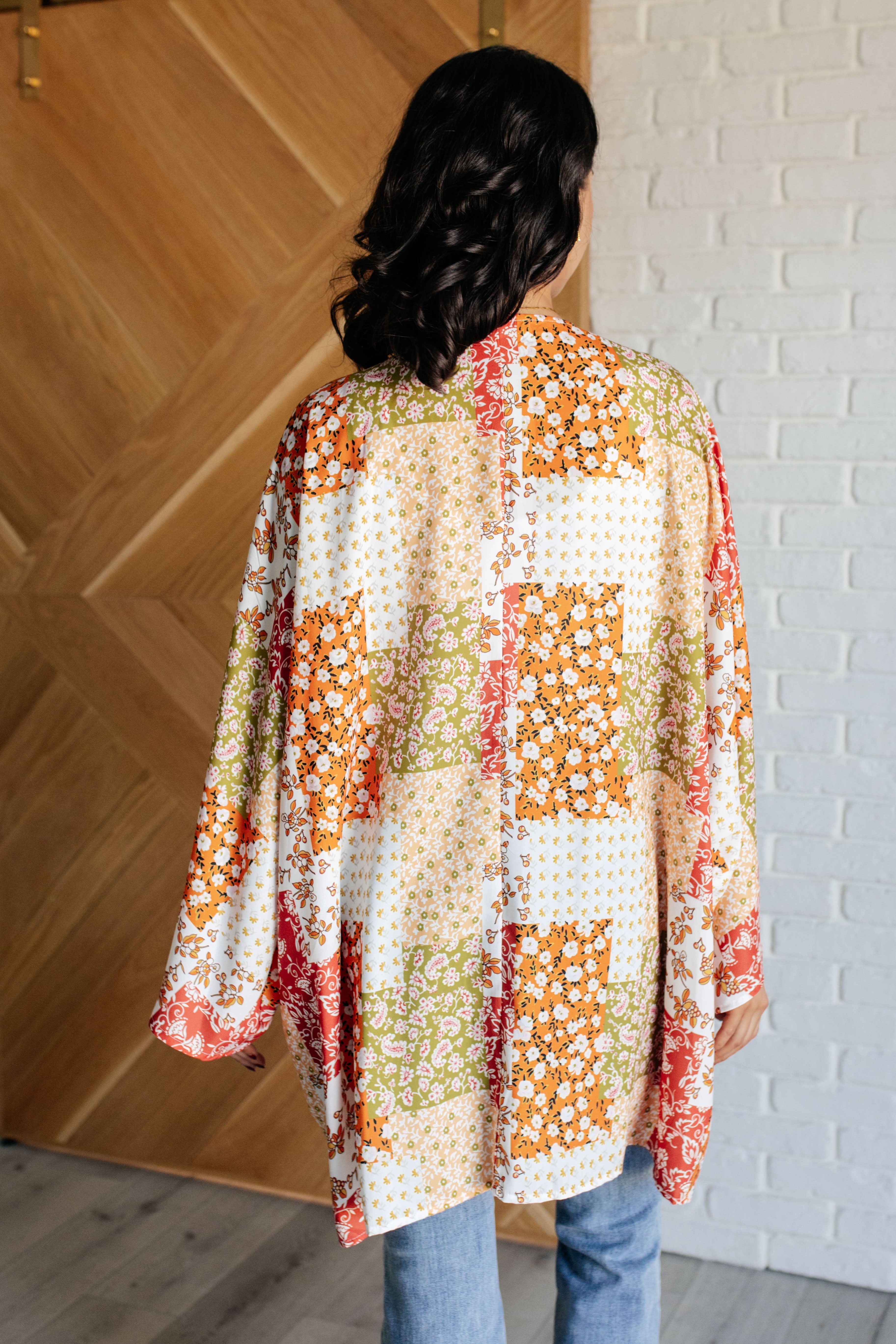 Rear view of woman wearing mixed floral patchwork duster with orange, green, and cream tones indoors