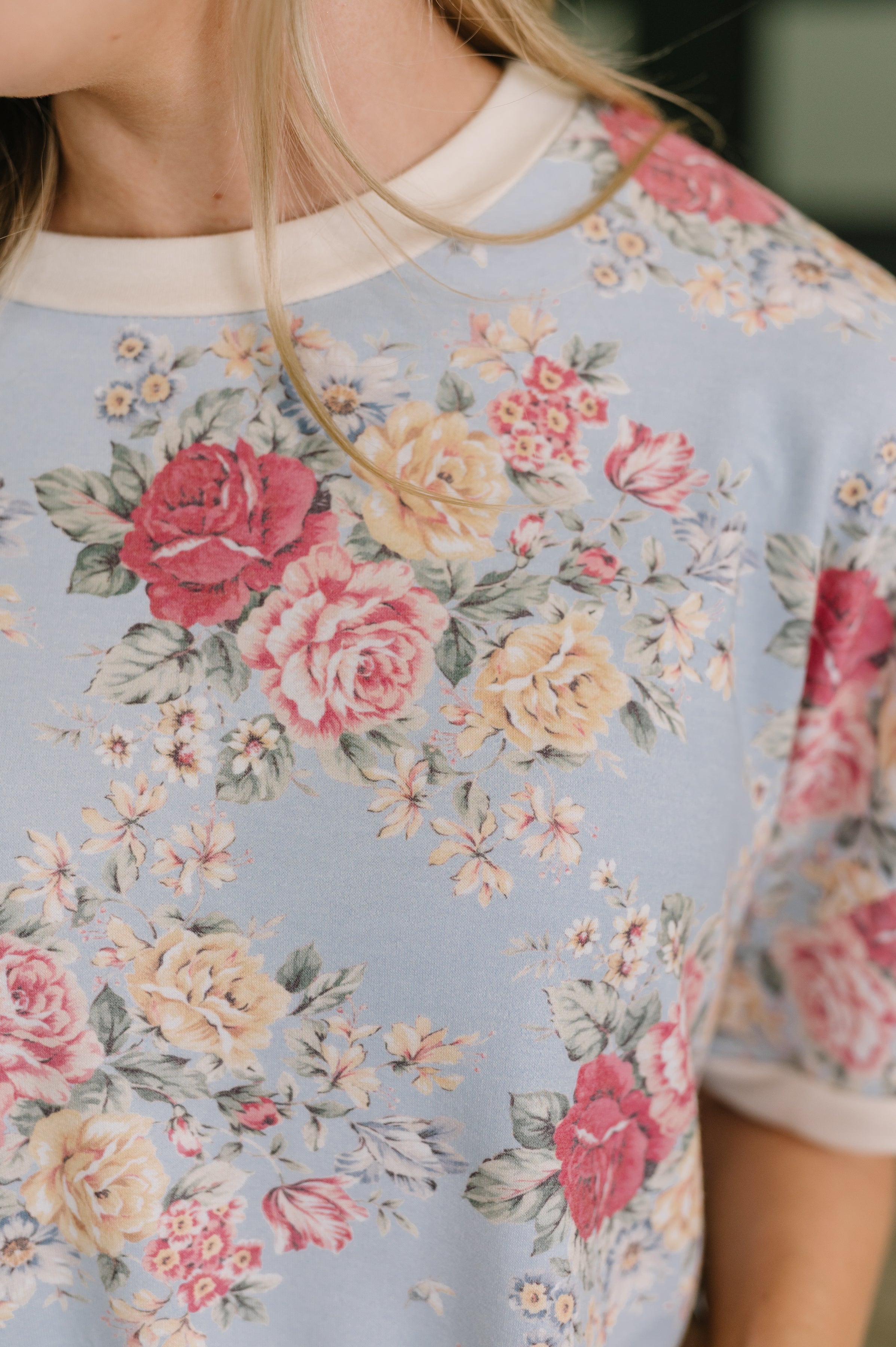 Close-up of soft blue relaxed tee with vintage-inspired floral print featuring roses and daisies on fabric