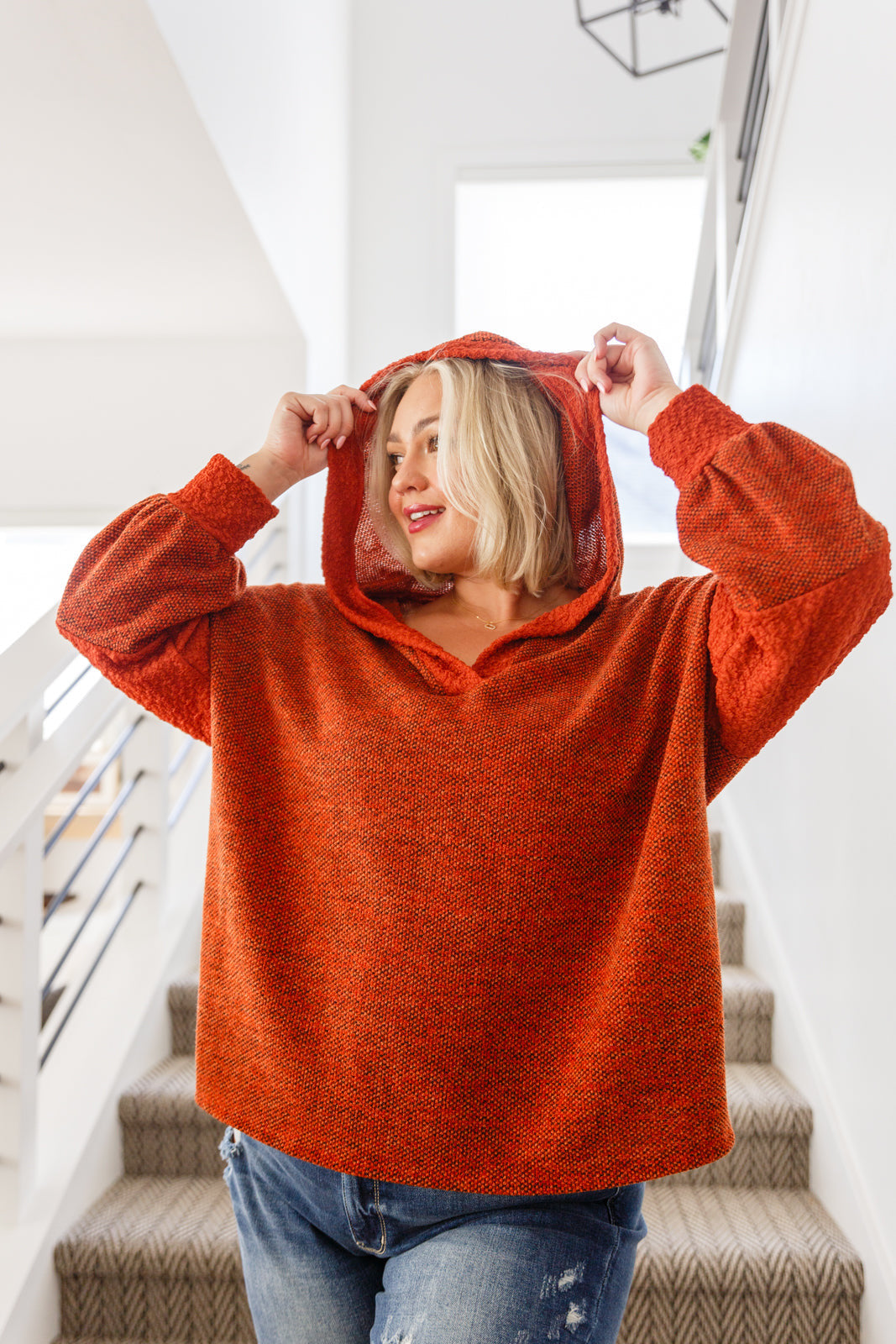 Woman wearing rust color block hoodie with textured knit fabric and hood in eclectic, size-inclusive style