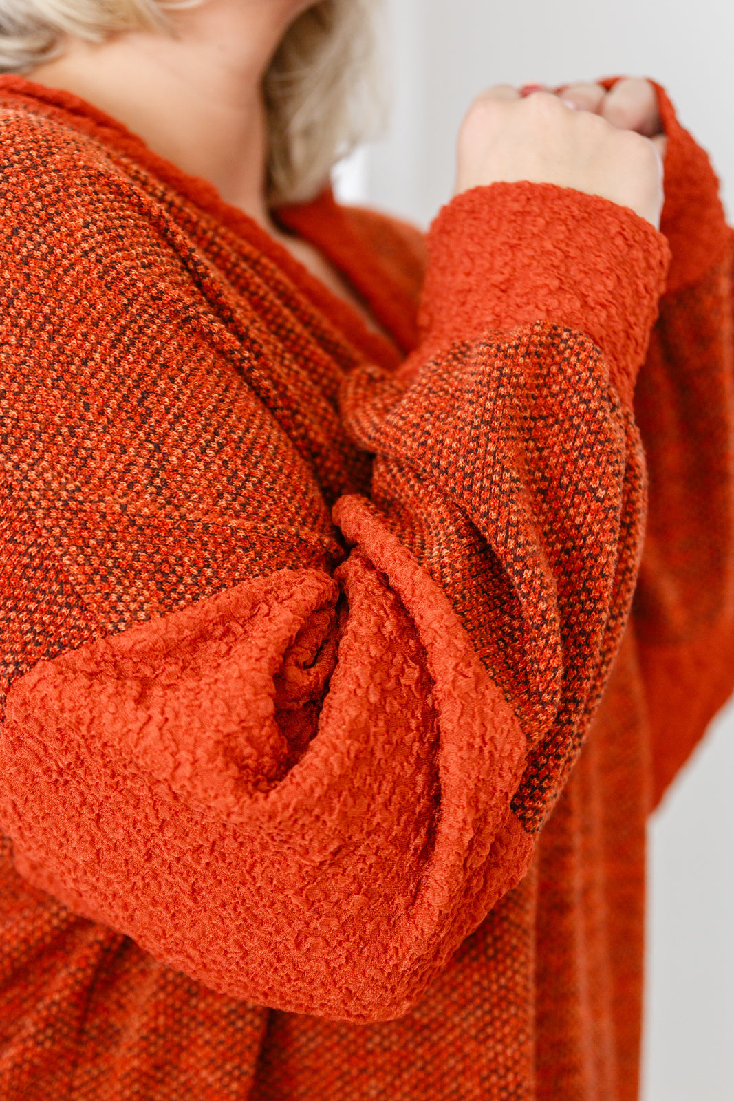 Close-up of rust color block hoodie sleeve in plush textured knit fabric with relaxed fit and eclectic style
