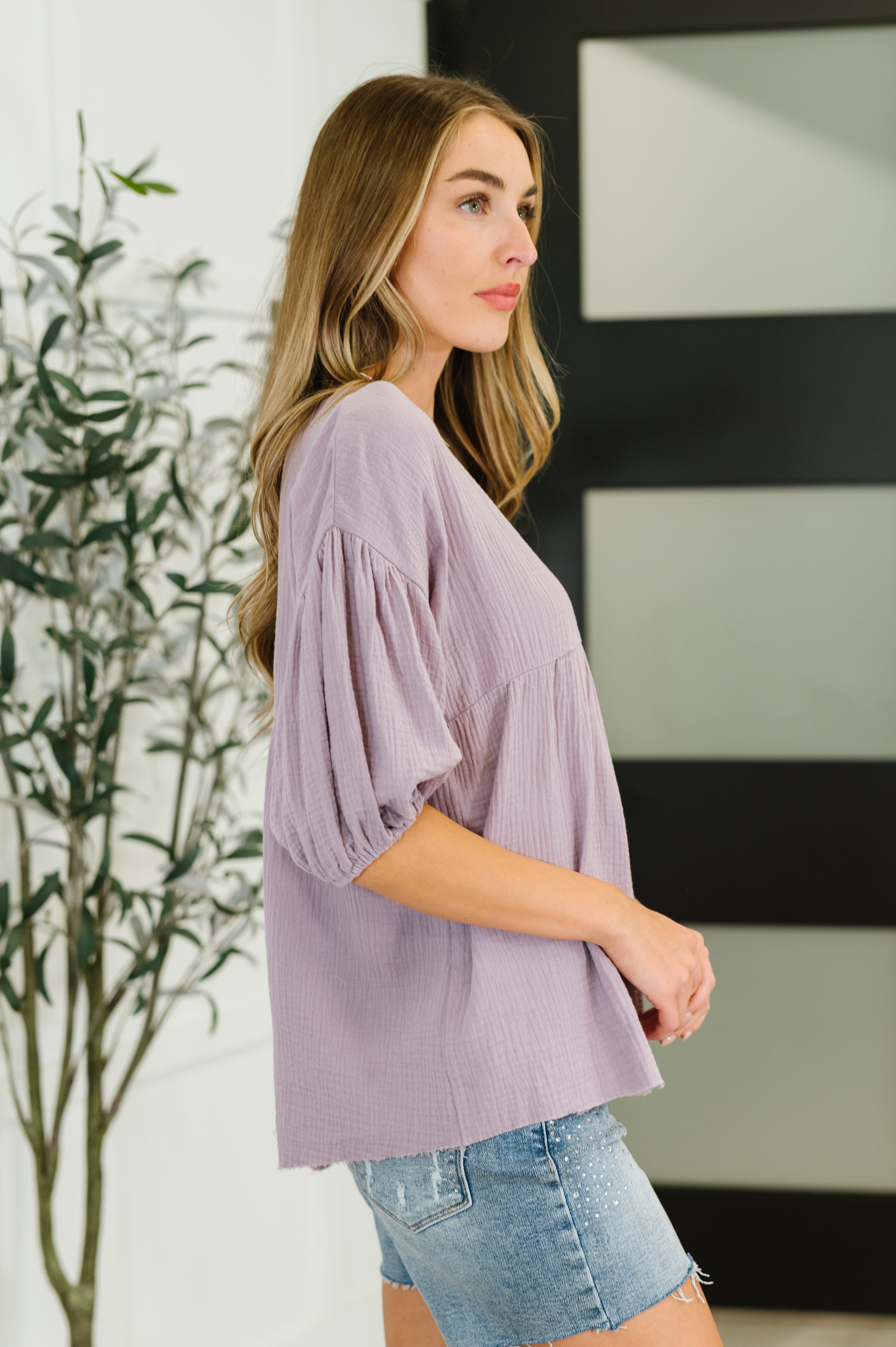 Woman wearing lavender bubble sleeve blouse with loose fit and textured fabric in eclectic, size-inclusive style