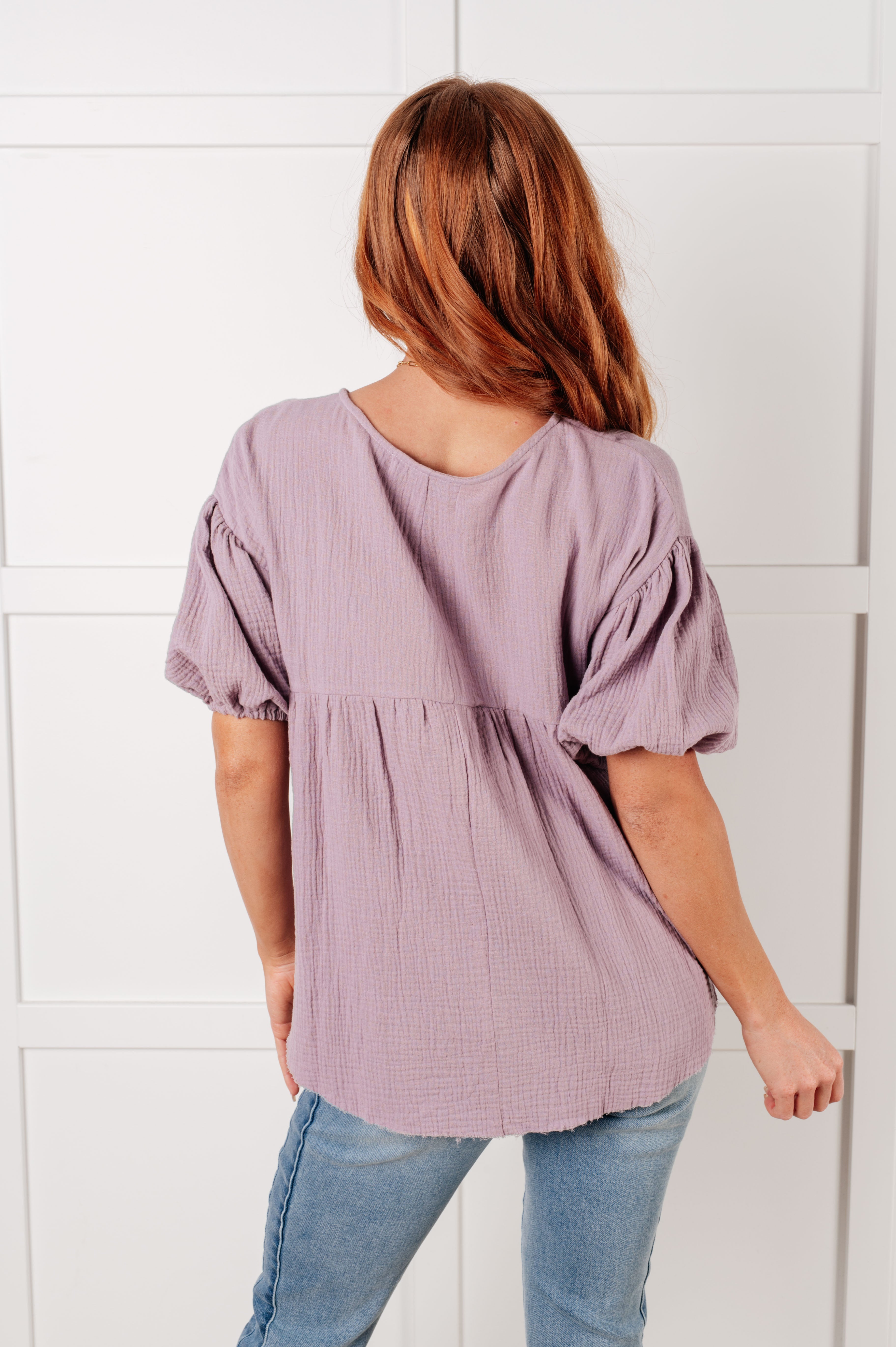 Woman wearing lavender bubble sleeve blouse with textured fabric in relaxed, size-inclusive, free-spirited style from back view